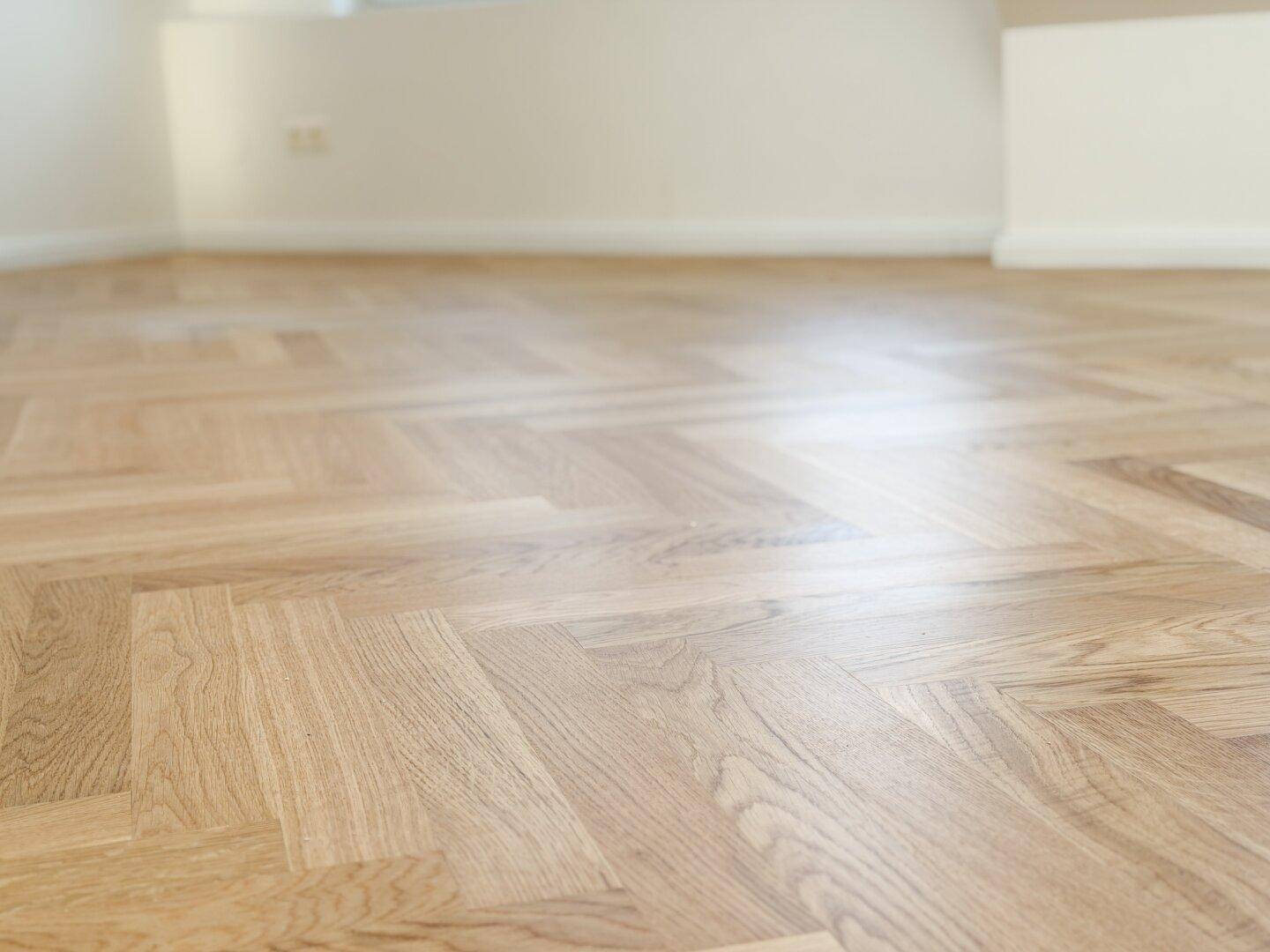 Detailaufnahme des eleganten Fischgrätparketts aus hellem Holz.