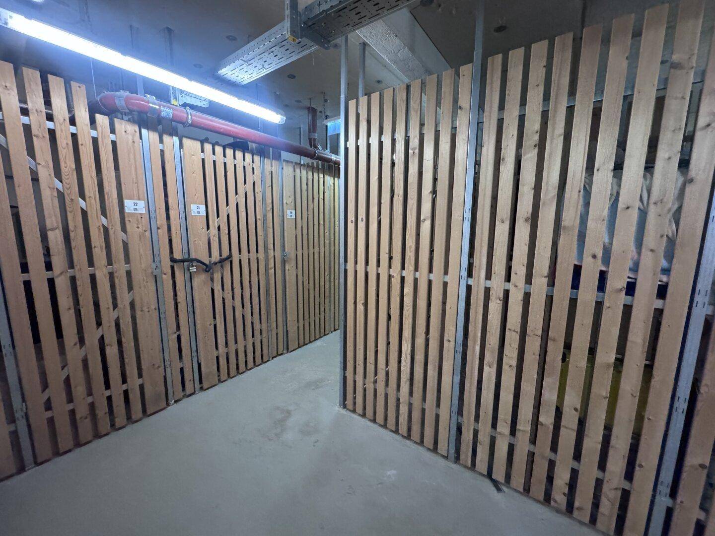 Abgetrennte Kellerabteile aus Holzlatten im Untergeschoss für zusätzlichen Stauraum.
