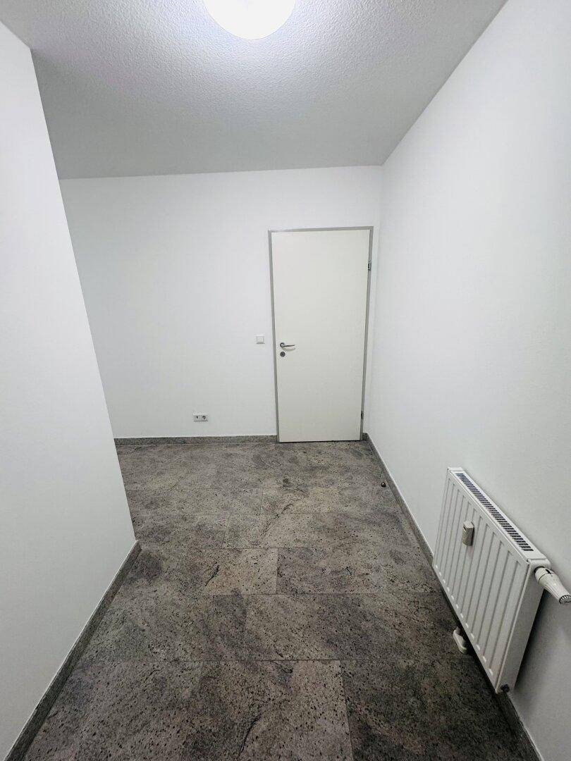 Eingangsbereich oder kleiner Flur mit Steinboden und weiß gestrichenen Wänden.