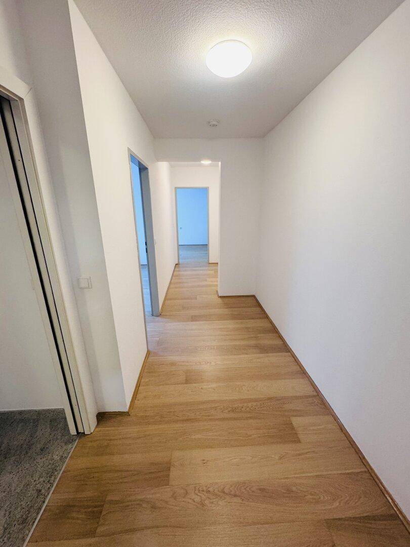 Langer, heller Flur mit Parkettboden, der zu weiteren Räumen führt.
