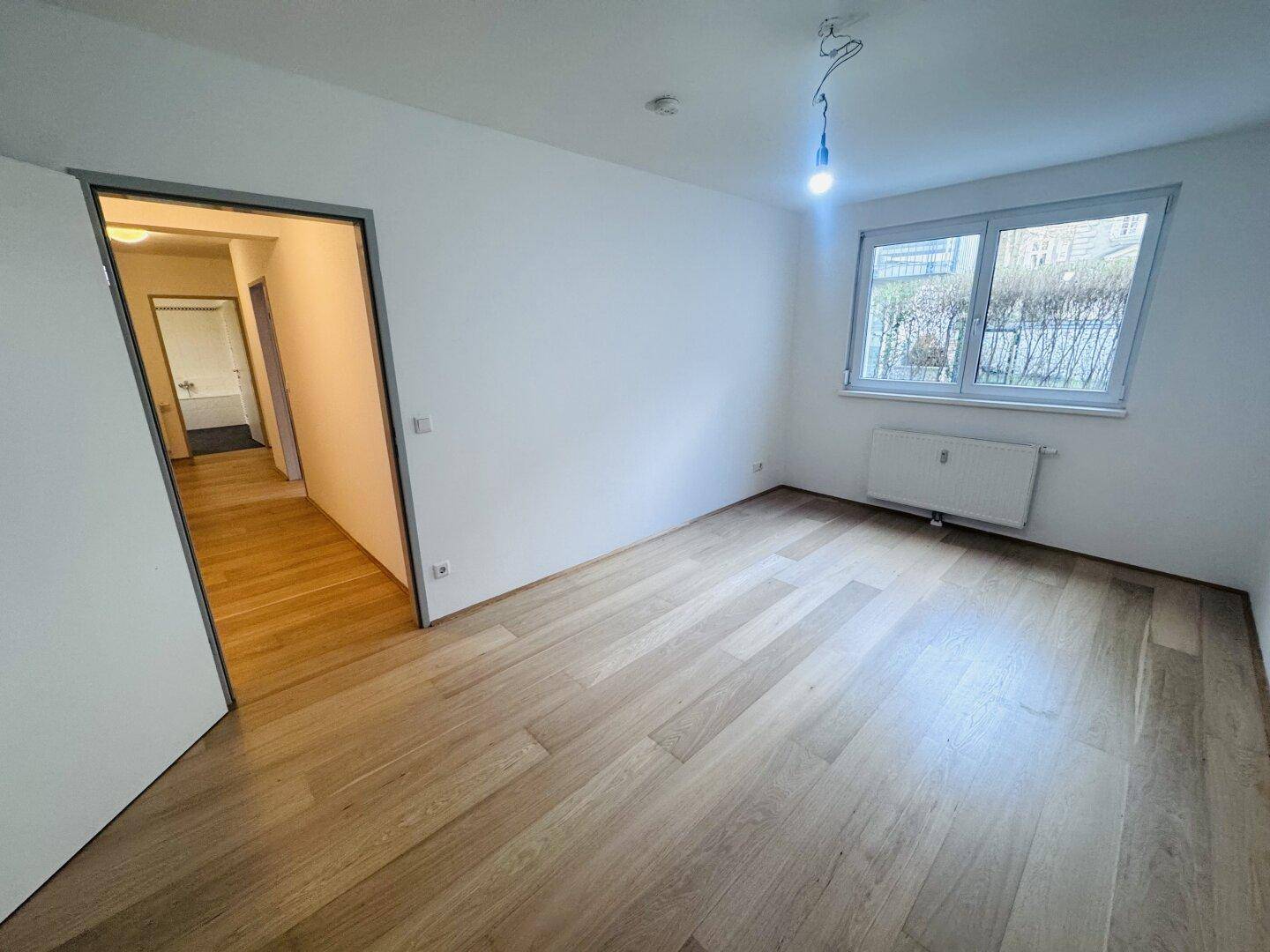 Geräumiges Schlafzimmer mit Holzboden und Zugang zum Flur, ideal für erholsame Nächte.