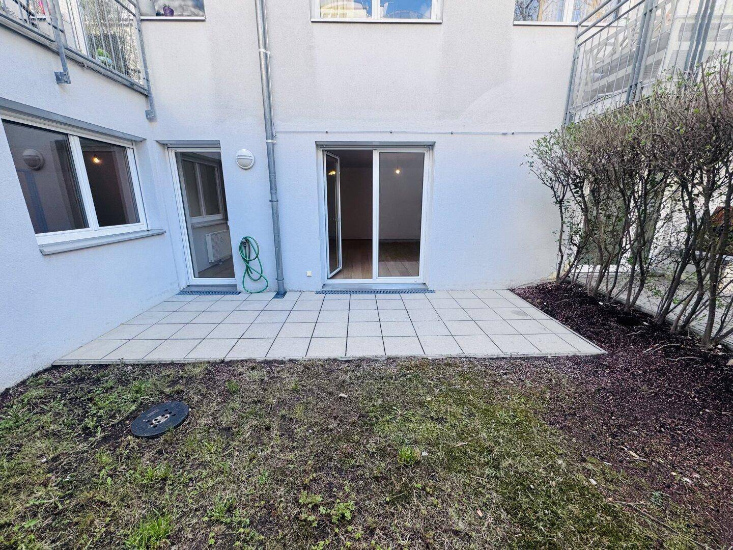 Gartenbereich mit Rasen und gepflasterter Fläche, direkt am Gebäude gelegen.