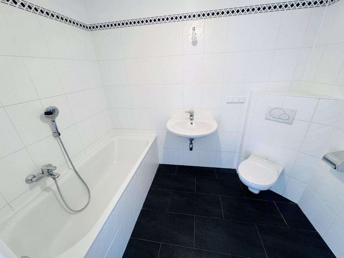 Badezimmer mit Badewanne, Waschbecken, WC und weißen Fliesen.
