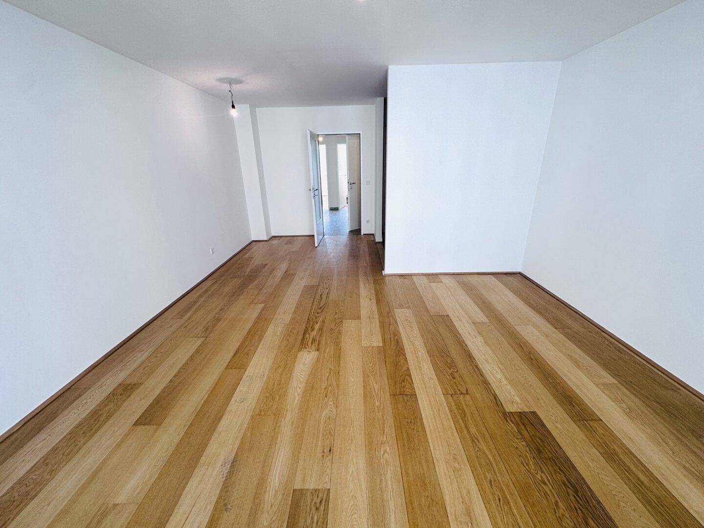 Helles Zimmer mit breiten Holzplanken und weiß gestrichenen Wänden.