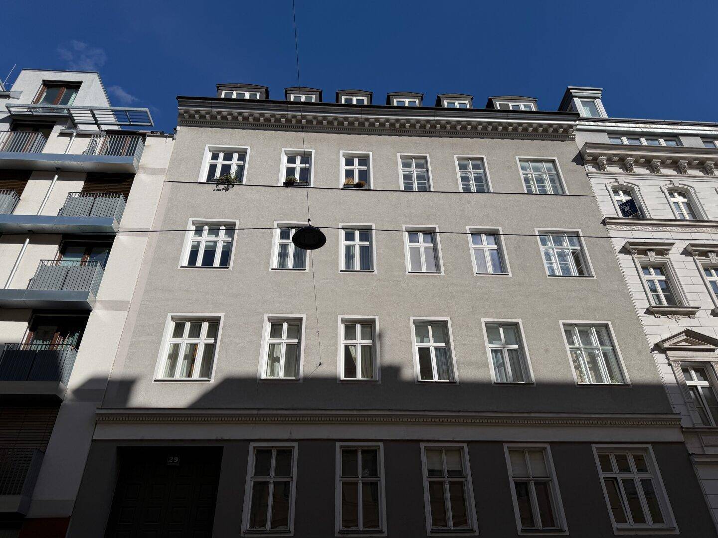 Historische Fassade eines Mehrfamilienhauses mit vielen Fenstern und klassischer Architektur.