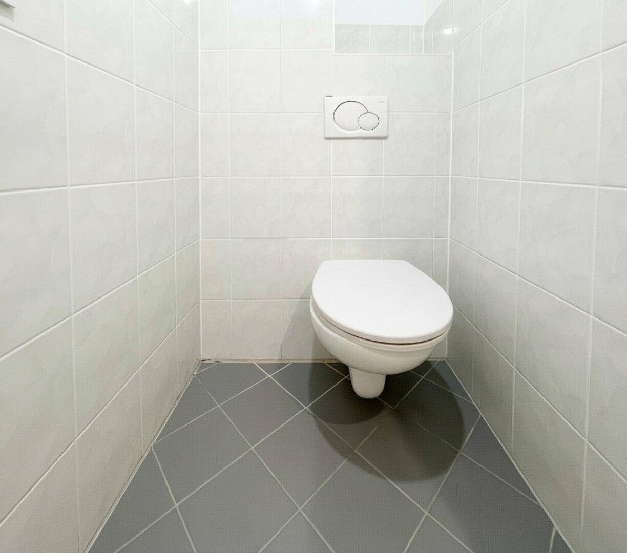 Modern gefliestes Gäste-WC mit wandhängender Toilette und hellen Fliesen.