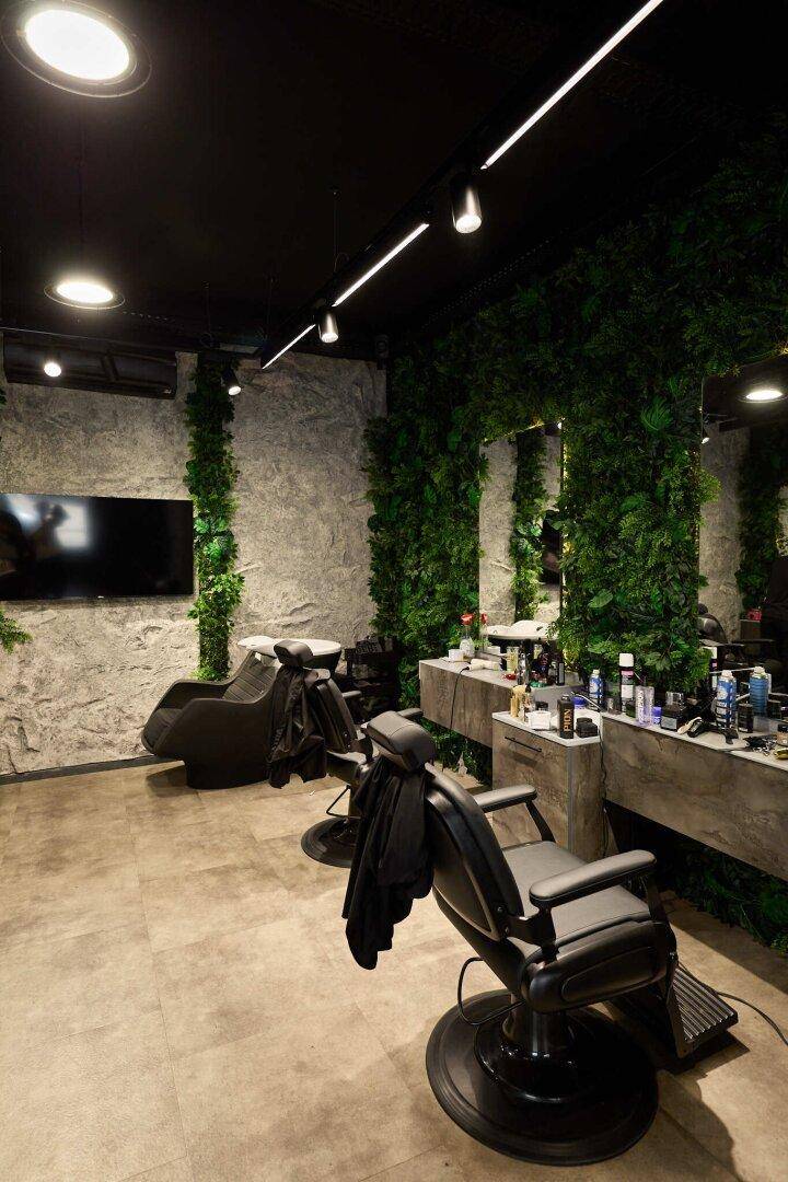 Moderner Innenraum mit dunkler Decke, strukturierten Wänden und Friseurstühlen.