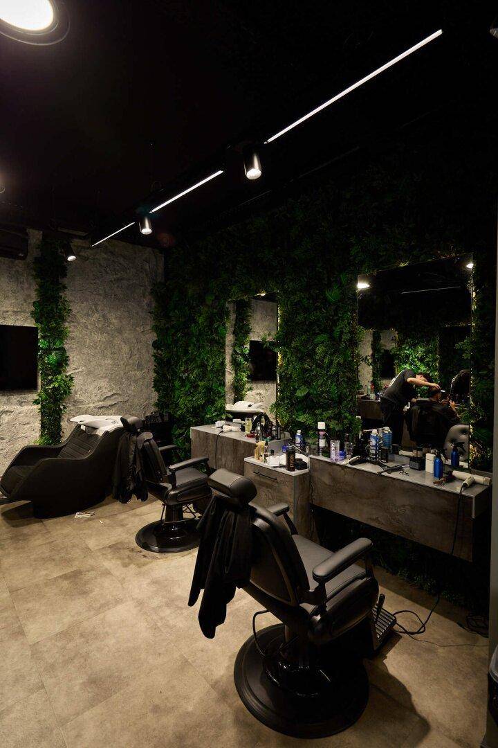 Moderner Friseursalon mit dunkler Decke, strukturierten Wänden und mehreren Arbeitsplätzen.