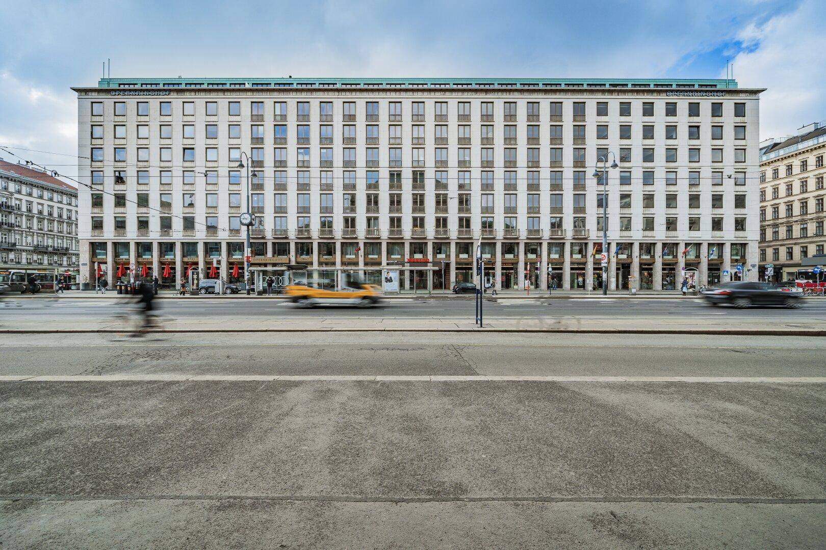 Großes, repräsentatives Gebäude mit vielen Fenstern und Geschäften im Erdgeschoss an einer belebten Straße.