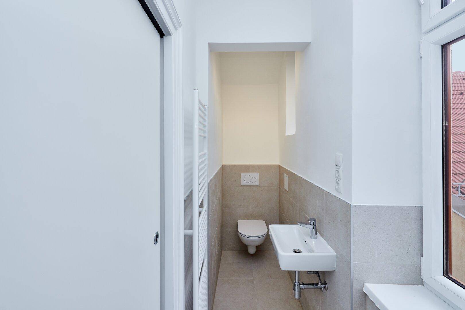 Modernes Gäste-WC mit wandhängender Toilette, kleinem Waschbecken und Fenster.