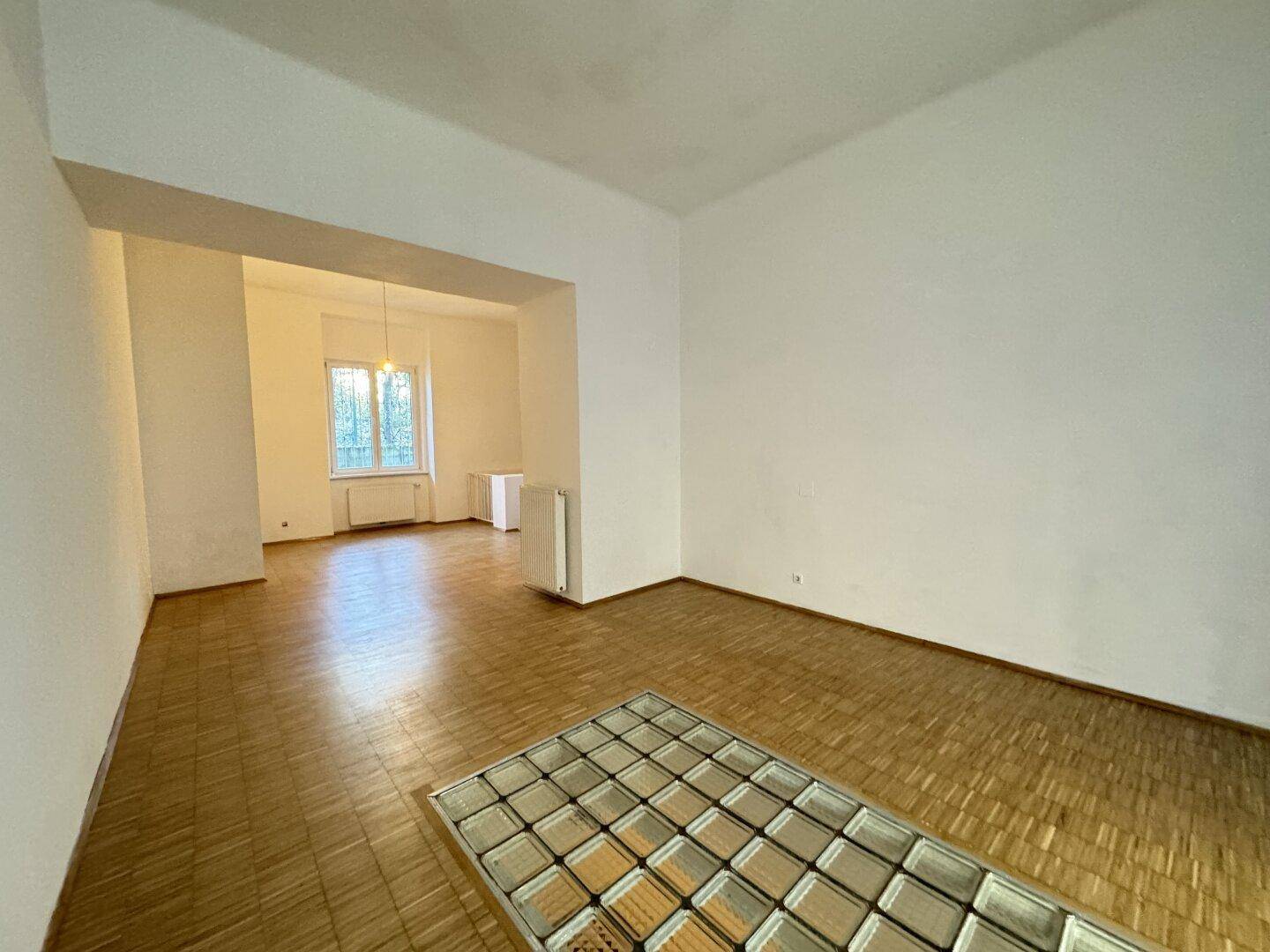 Geräumiger Wohnbereich mit Holzparkett und einem dekorativen Glasbaustein-Element im Boden.