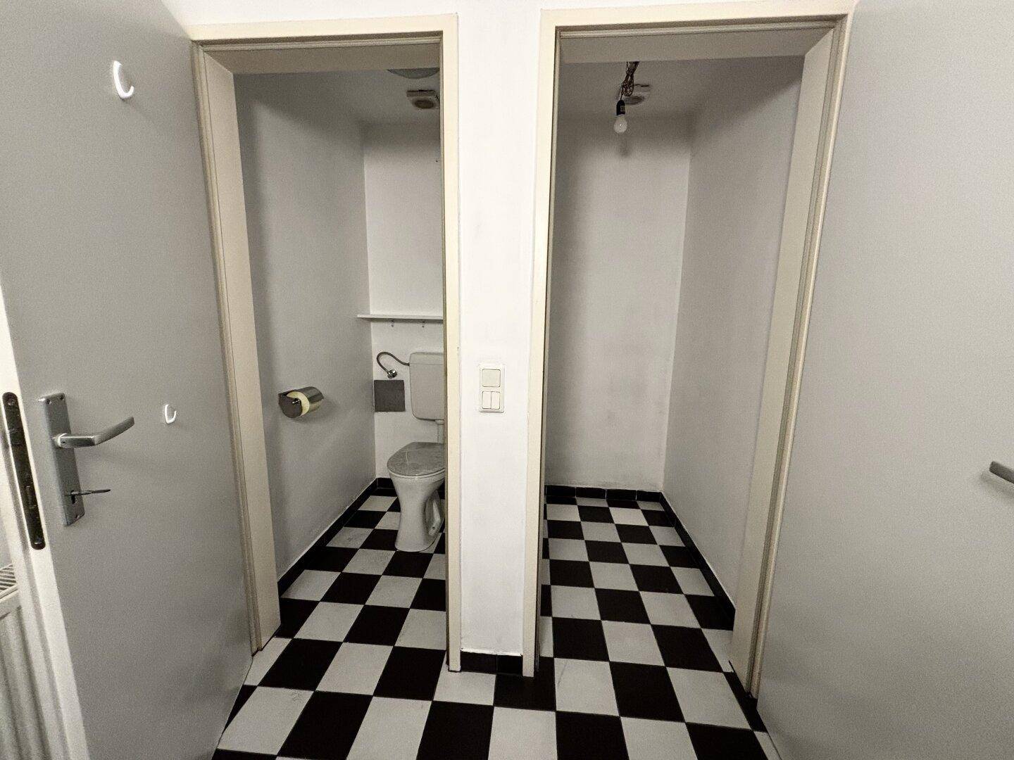 Zwei separate Toilettenräume mit schwarz-weiß kariertem Fliesenboden und Wand-WCs.