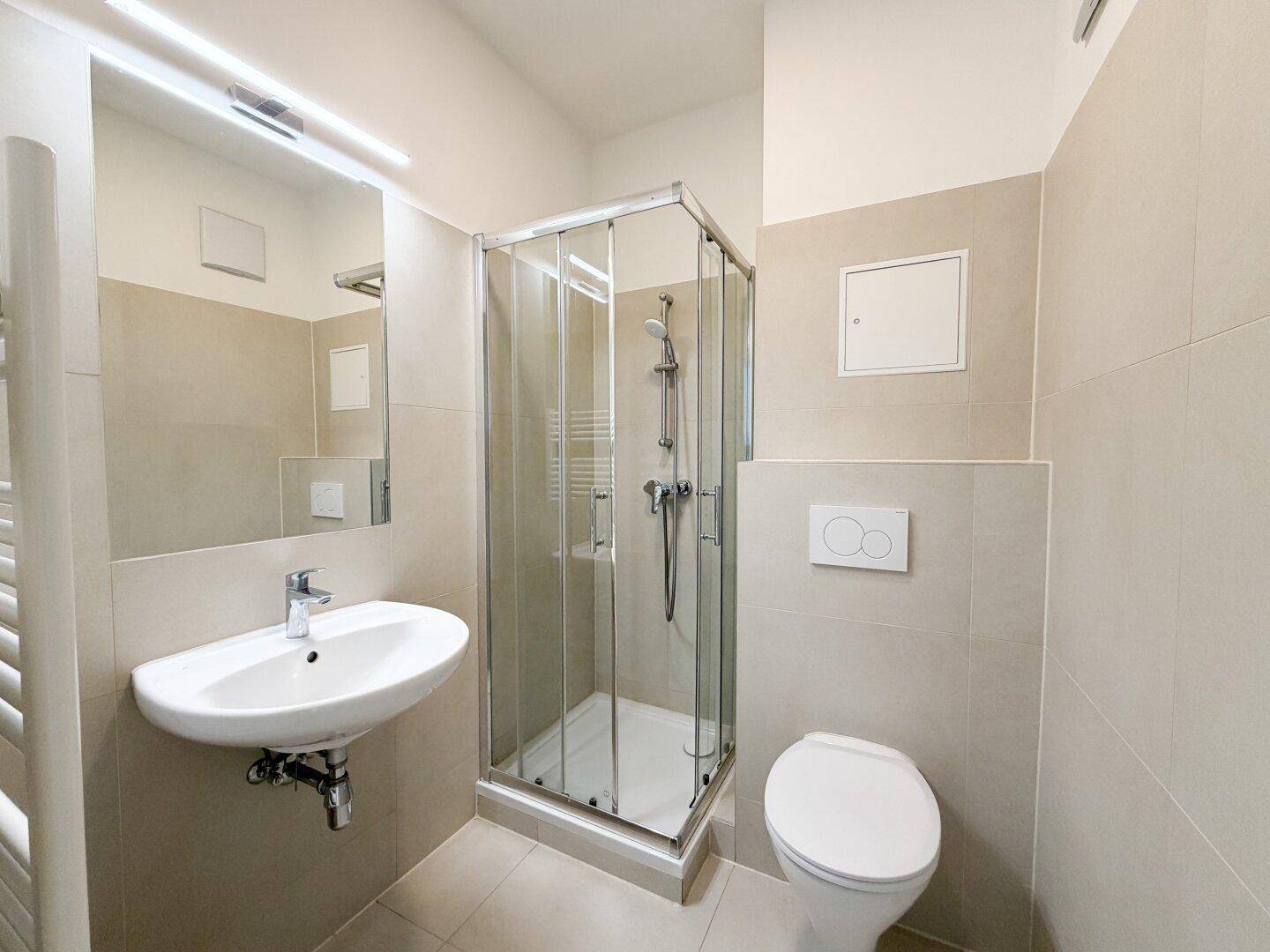 Helles Badezimmer mit Duschkabine, WC, Waschbecken und großem Spiegel.