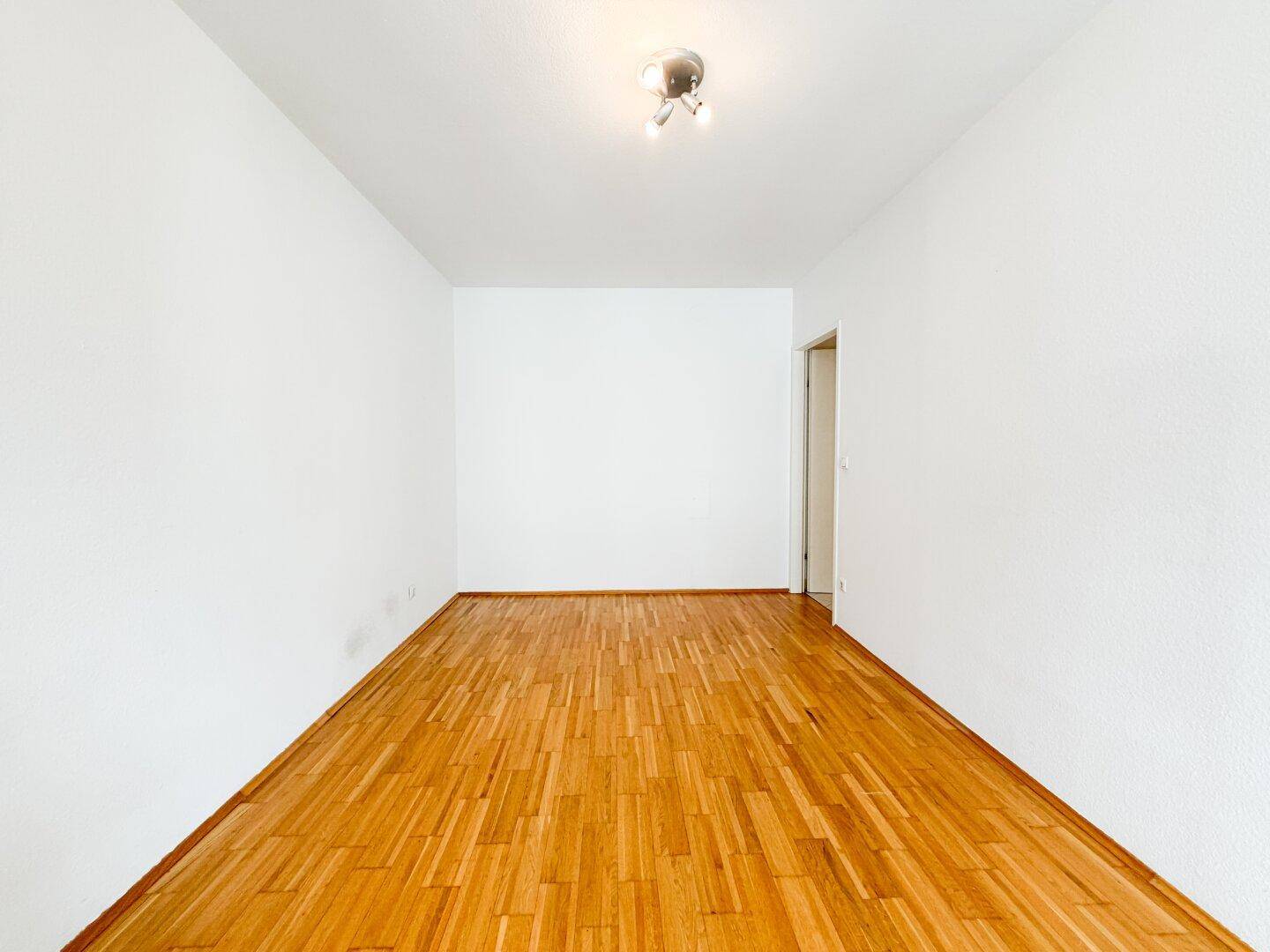 Helles Zimmer mit Parkettboden und weiß gestrichenen Wänden, bereit zur Einrichtung.