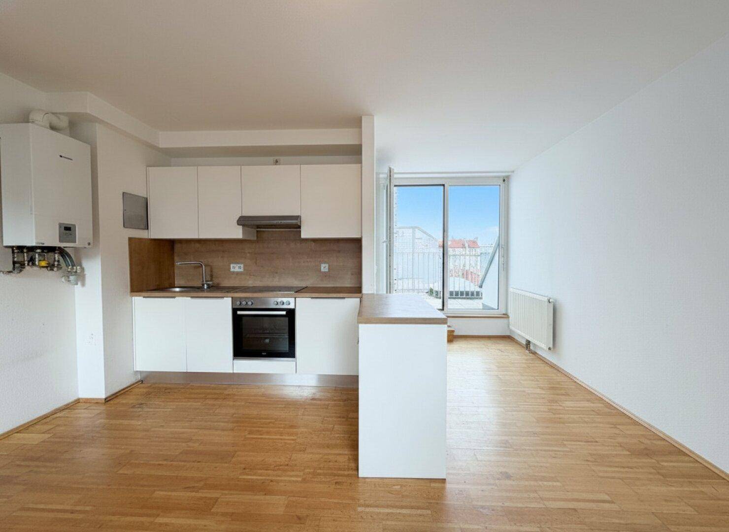 Helle Küche mit weißen Schränken, Holzarbeitsplatte und Zugang zu einem Balkon.