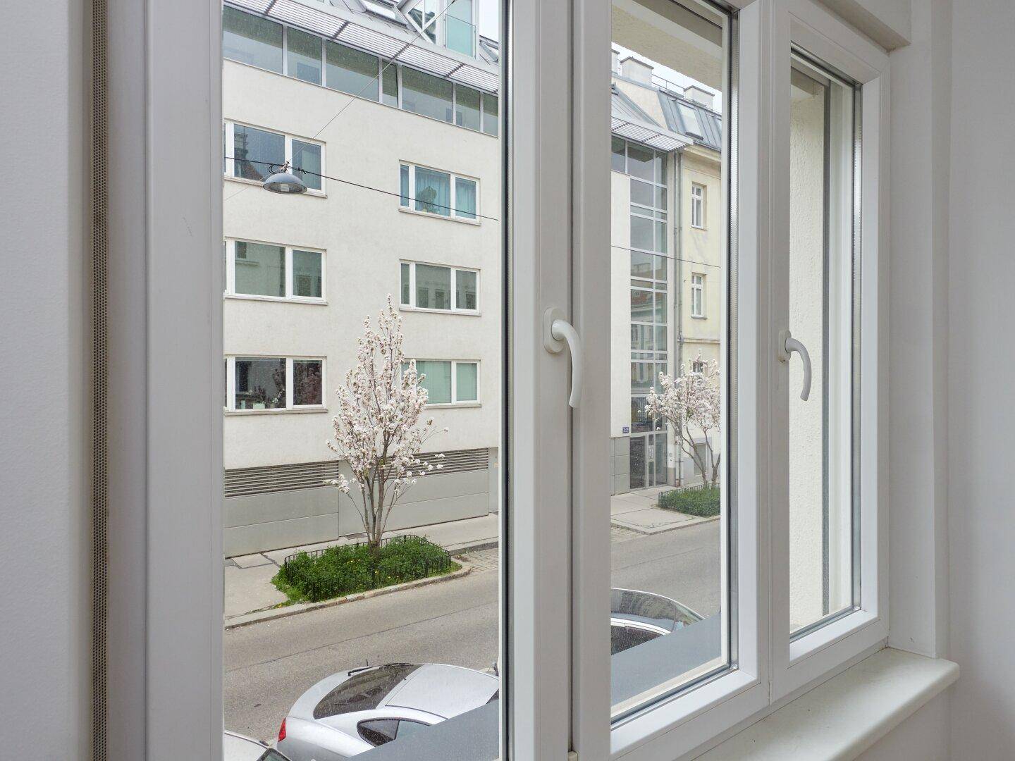 Blick aus dem Fenster auf eine ruhige Straße und gegenüberliegende Gebäude.