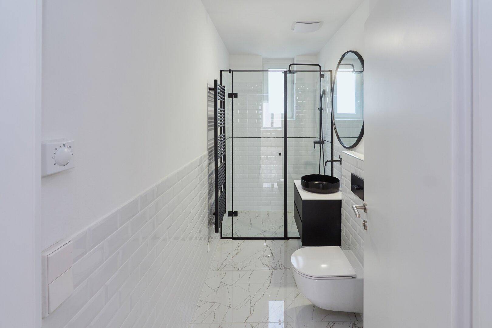 Modernes Badezimmer mit begehbarer Dusche, Wand-WC und stilvollen schwarzen Details.