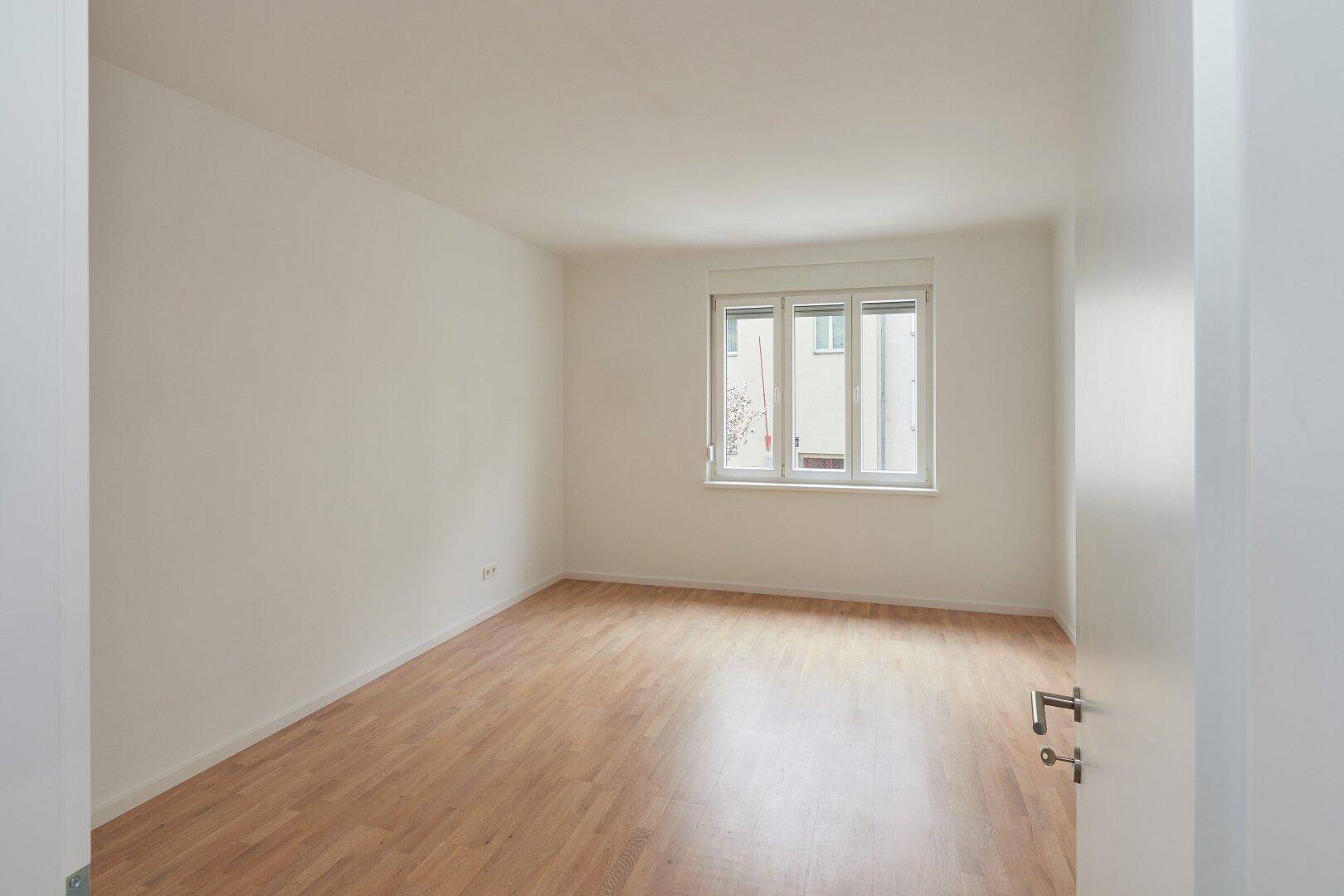 Helles, geräumiges Zimmer mit Parkettboden und großen Fenstern, ideal für vielfältige Nutzung.