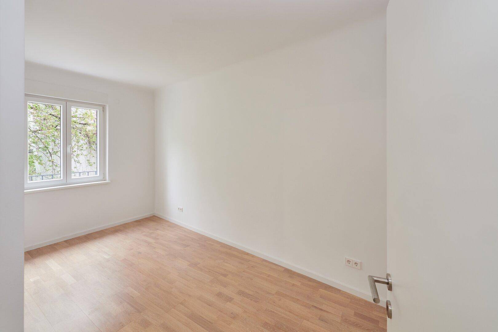 Helles Zimmer mit Parkettboden und Blick ins Grüne, ideal als Schlaf- oder Arbeitszimmer.