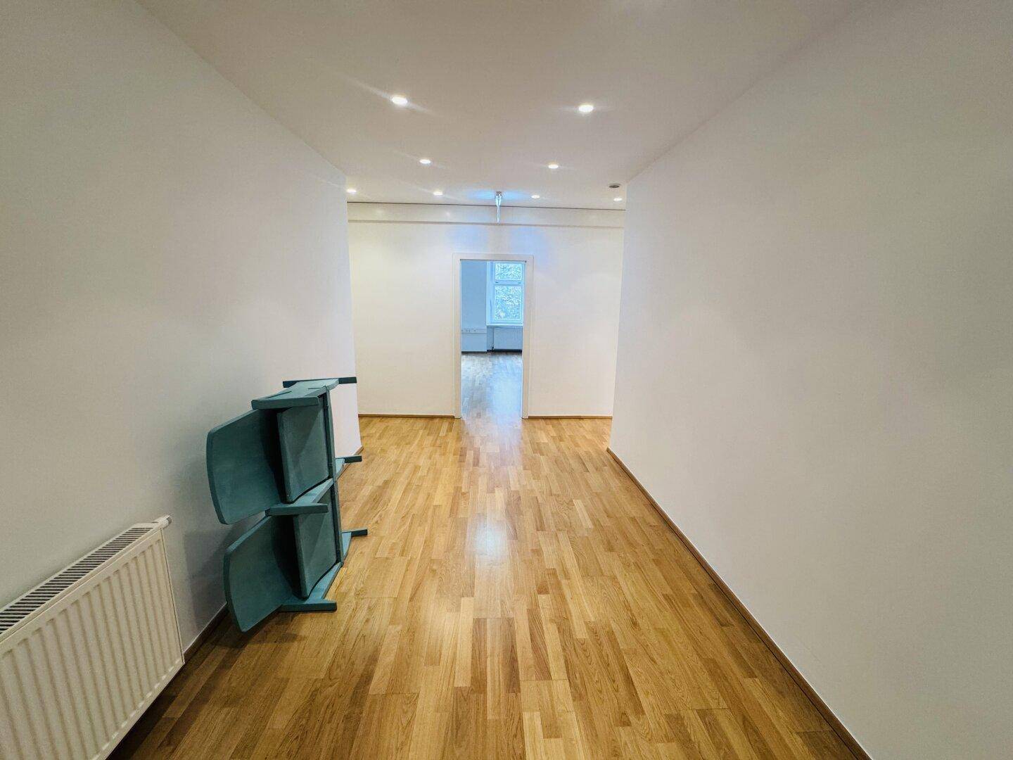 Langer, heller Flur mit Holzparkettboden und moderner Deckenbeleuchtung, der zu weiteren Räumen führt.