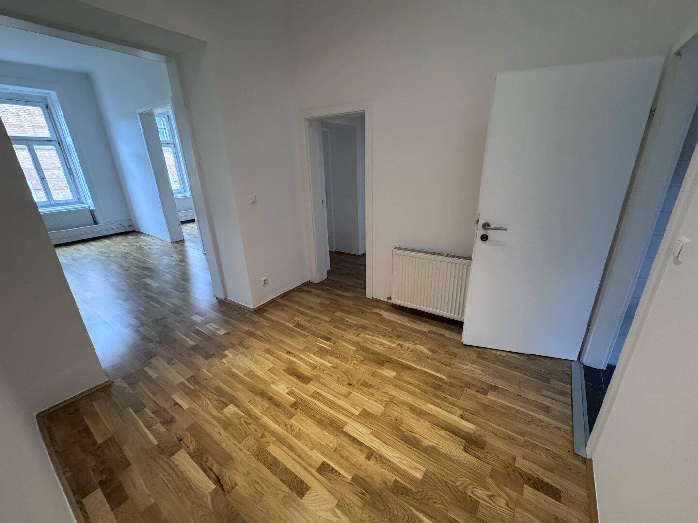 Geräumiger Flur mit Holzboden und Zugang zu mehreren Zimmern, hell und einladend.