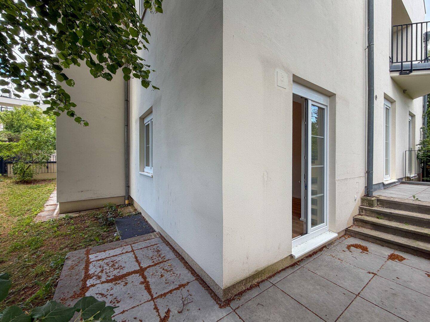Eckbereich des Hauses mit gepflasterter Terrasse und direktem Zugang zum Garten.