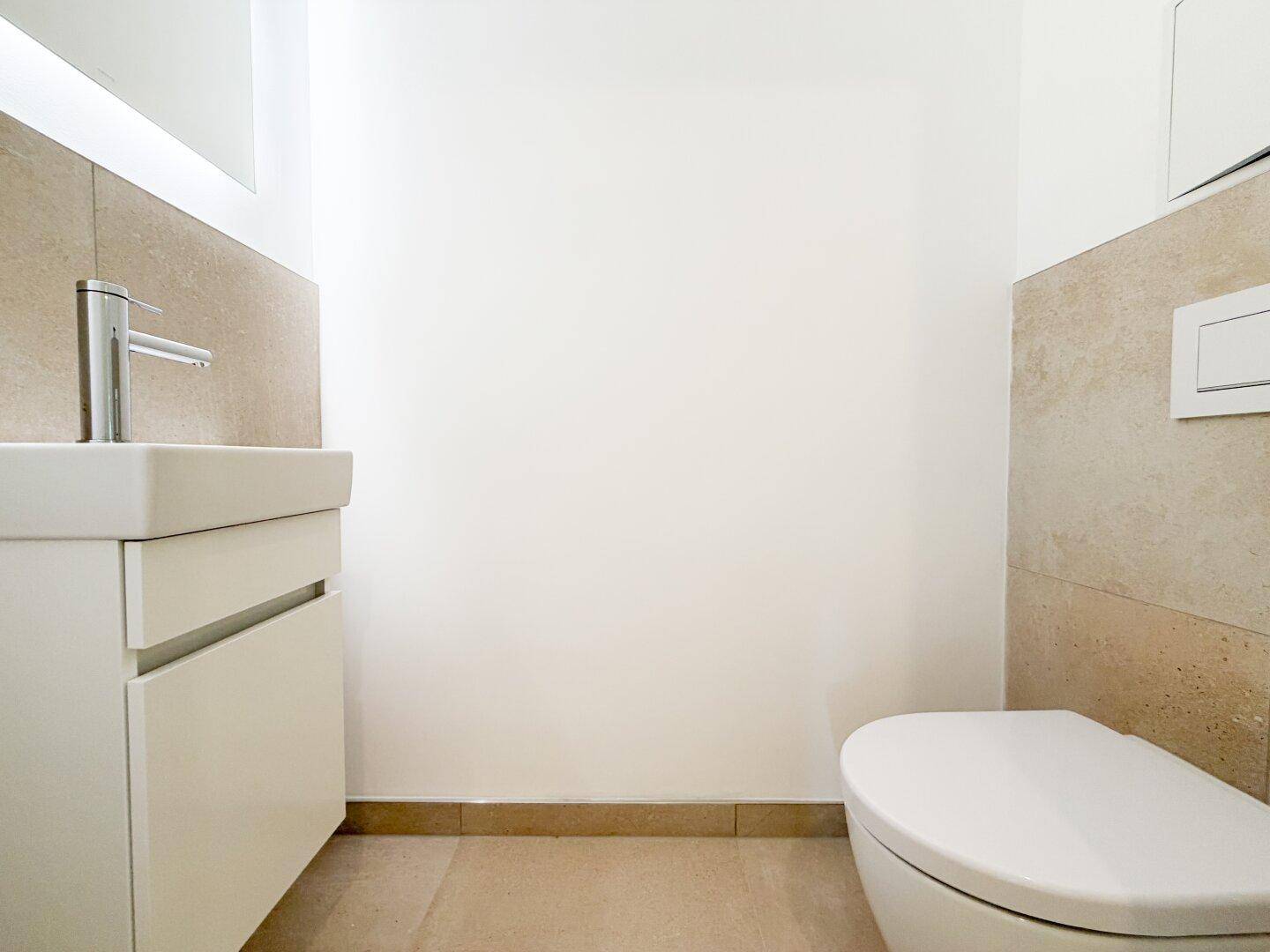 Helles Gäste-WC mit modernem Waschbecken und Wand-WC, ausgestattet mit beigefarbenen Fliesen.