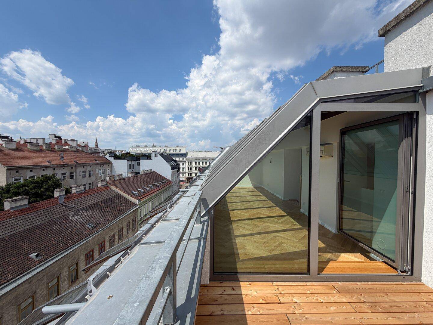 Dachterrasse mit Holzboden und Glasfront, die einen Übergang zum Innenbereich schafft.