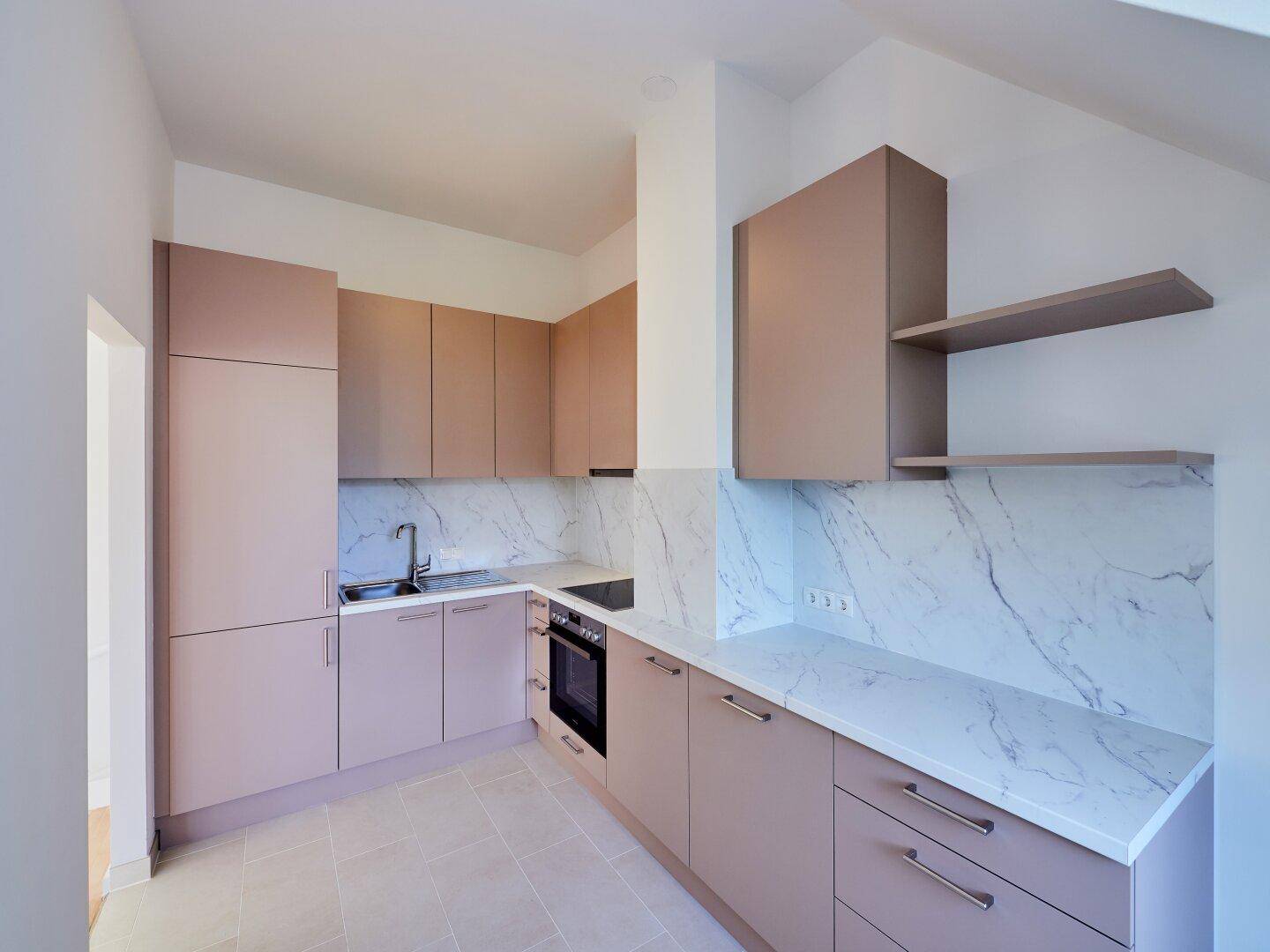 Voll ausgestattete moderne Küche mit hellbraunen Fronten und eleganten Marmor-Arbeitsplatten und Rückwand.