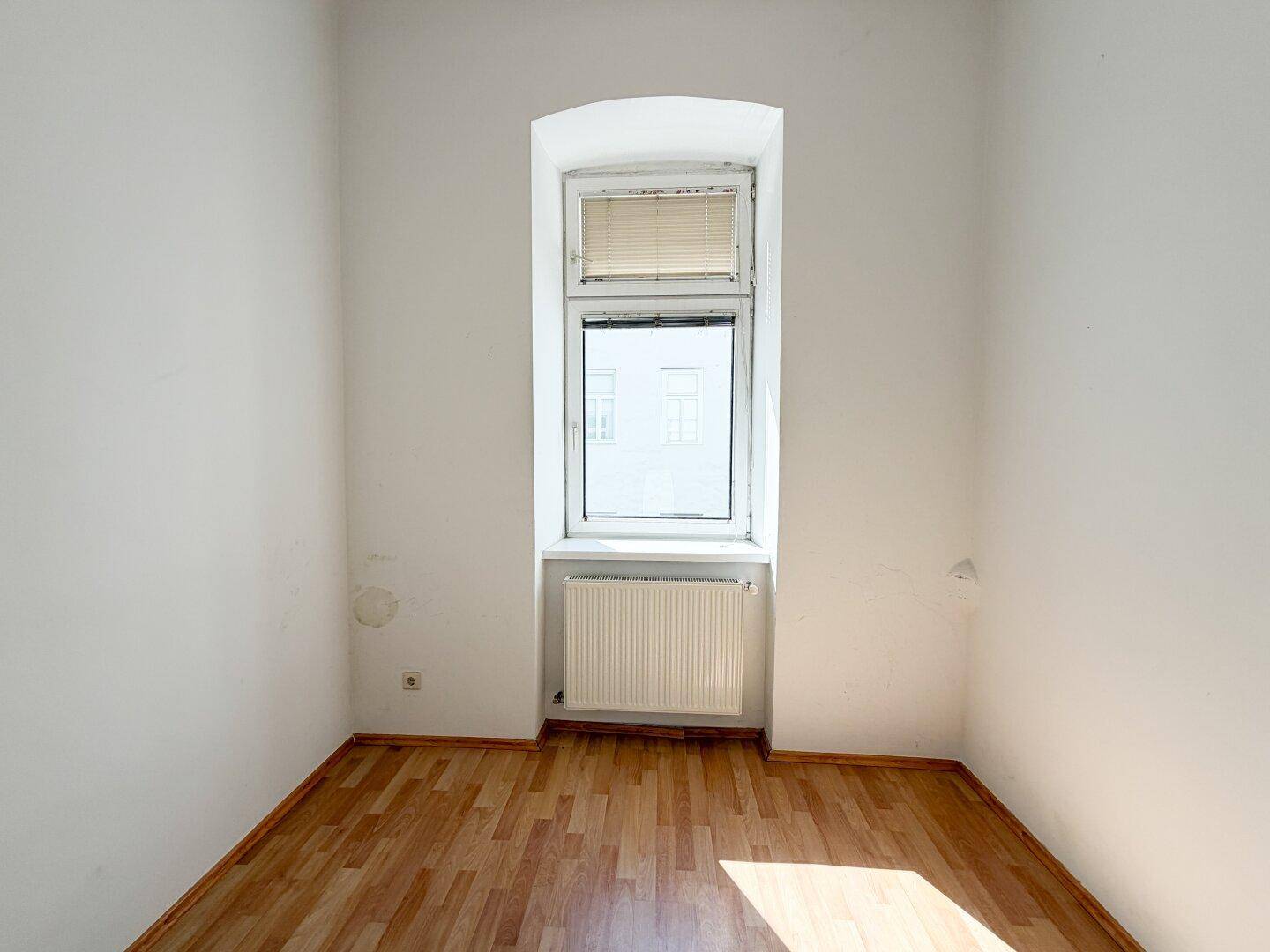 Kleines, helles Zimmer mit Laminatboden und einem Fenster, ideal als Kinder- oder Arbeitszimmer.