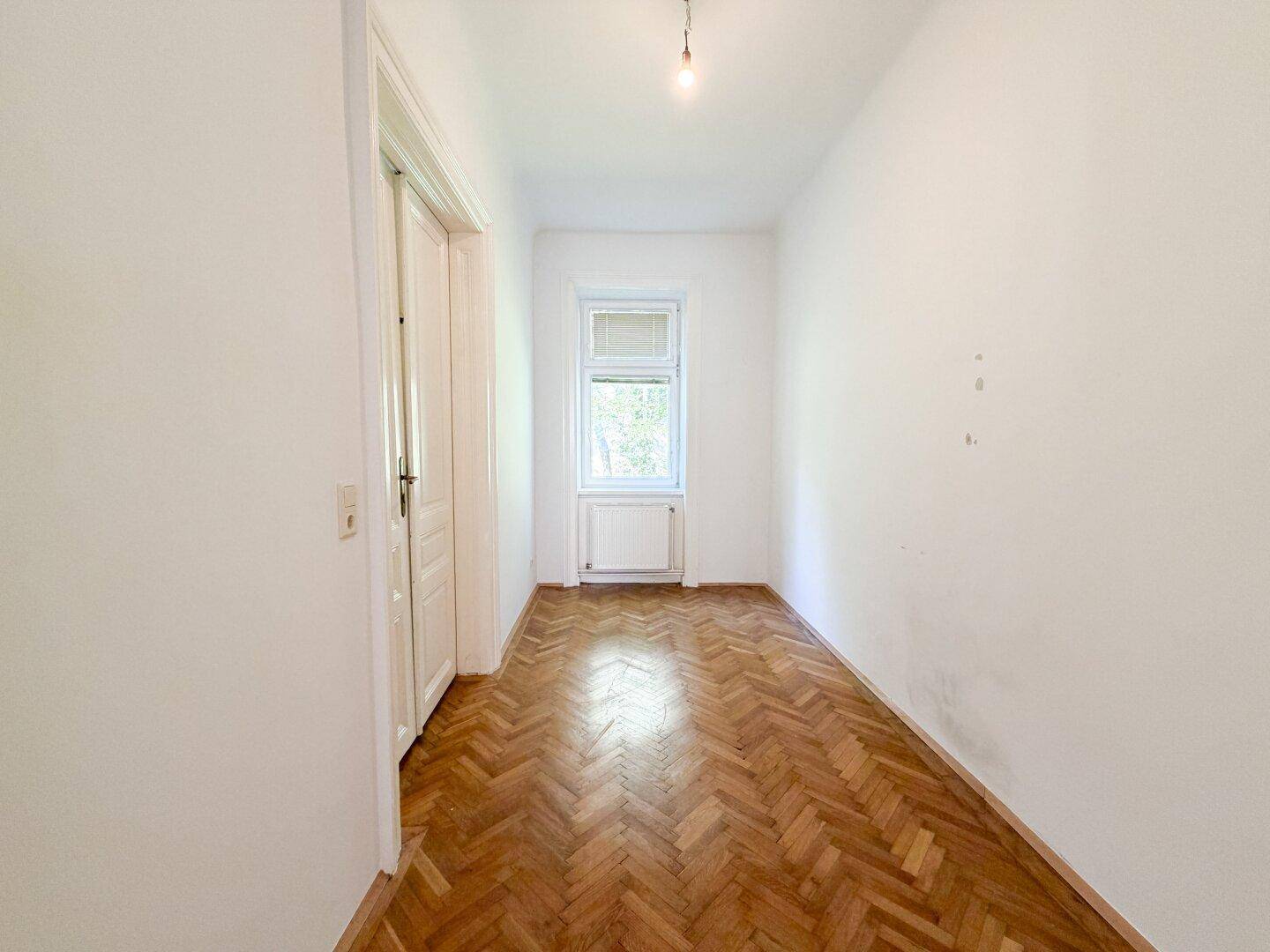 Helles Schlafzimmer mit Fischgrätparkett und Blick ins Grüne, bereit zum Einzug.