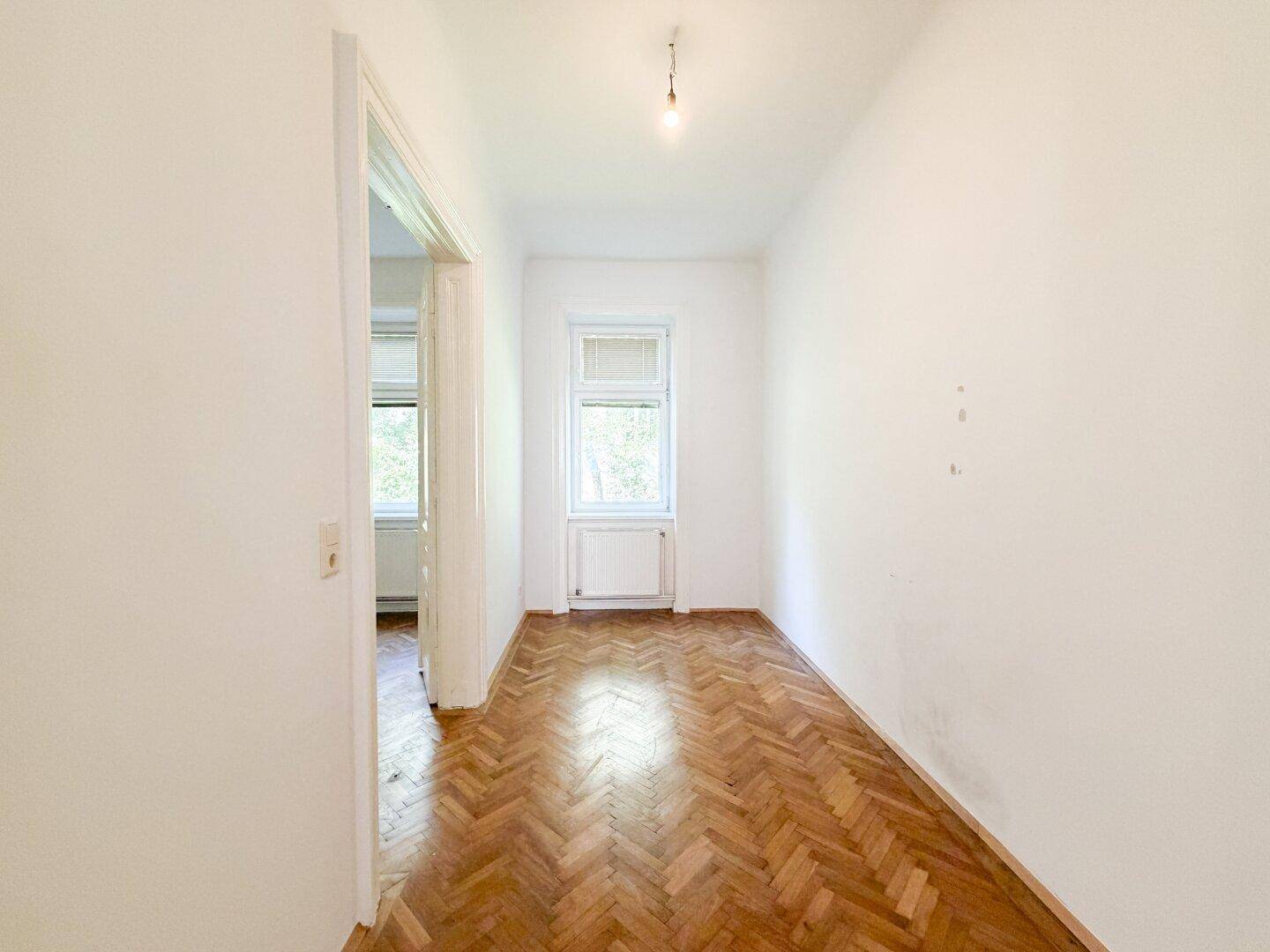 Gemütliches Zimmer mit Fischgrätparkett und einem Fenster, ideal als Schlaf- oder Arbeitszimmer.