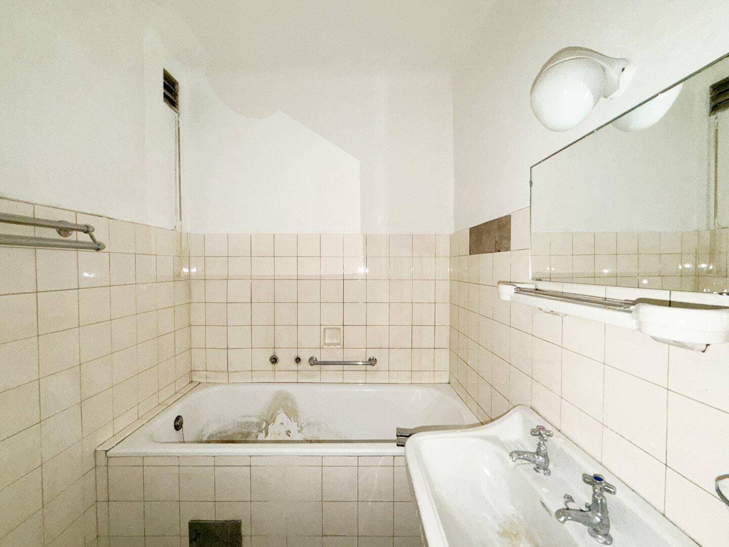 Badezimmer mit Badewanne, Waschbecken und Heizkörper, zeigt klassische Fliesen und Armaturen.