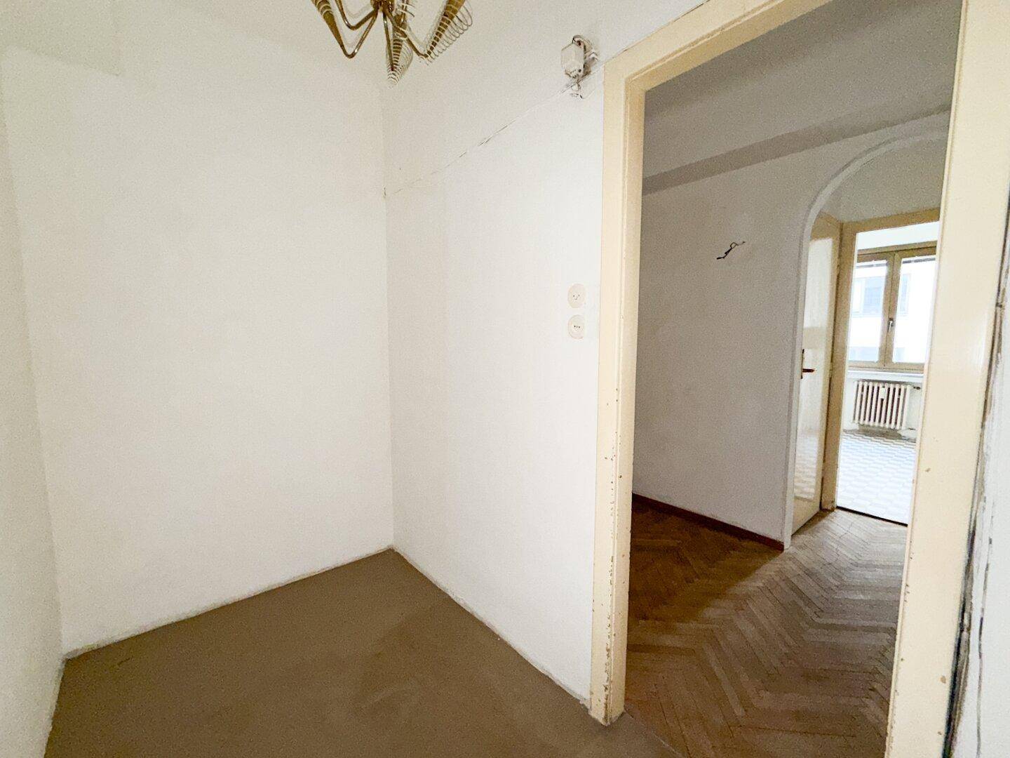 Kleiner Raum mit einfachem Bodenbelag und Zugang zu einem Zimmer mit Parkett.
