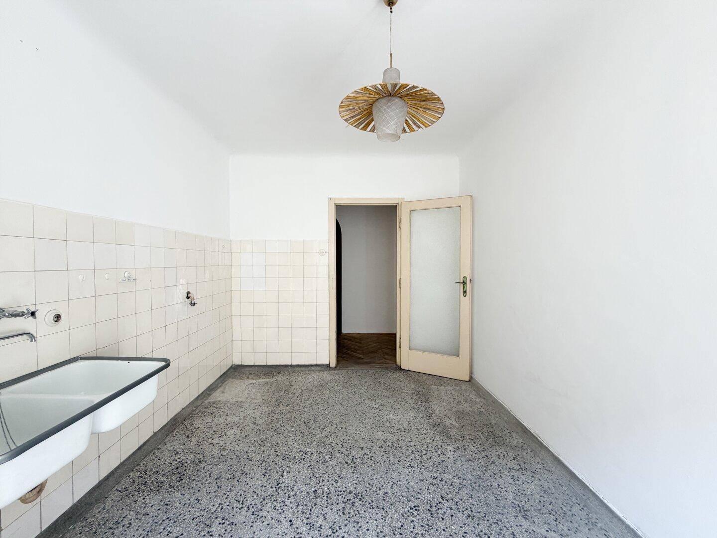 Geräumige leere Küche mit Doppelwaschbecken und gefliestem Bereich, ideal für individuelle Gestaltung.