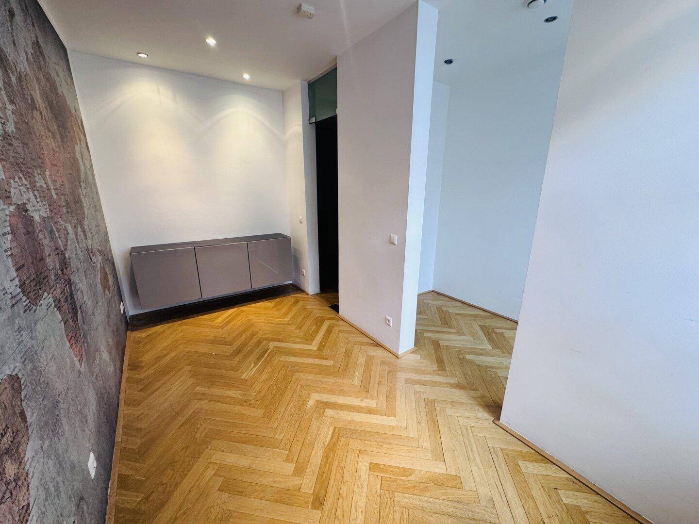 Heller Raum mit Fischgrätparkett, einer dekorativen Weltkartenwand und einem schwebenden Sideboard.