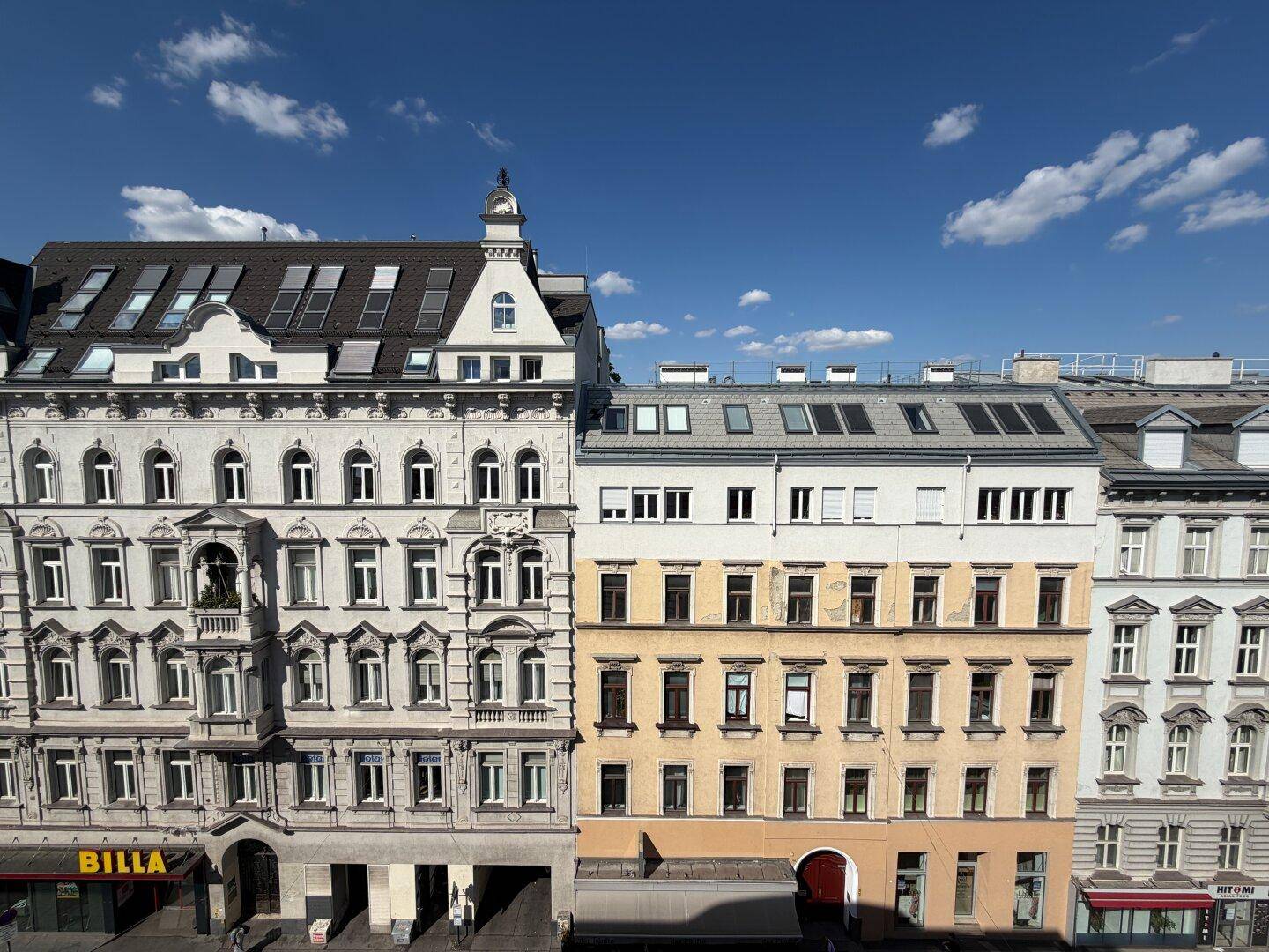 Historische Gebäudezeile mit detailreichen Fassaden und traditioneller Architektur unter blauem Himmel.