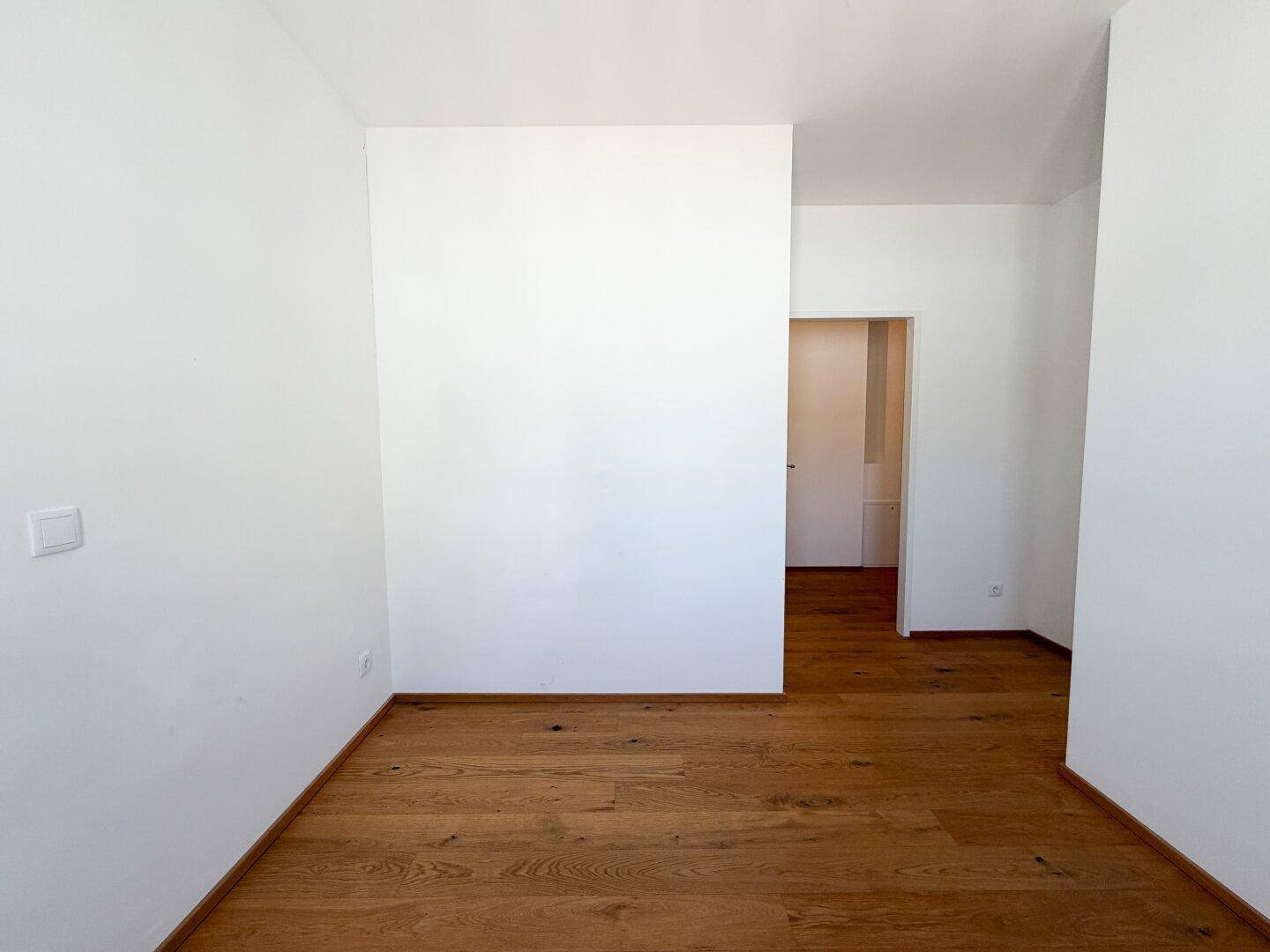 Geräumiges Zimmer mit hellem Holzboden und weiß gestrichenen Wänden, bereit zur individuellen Gestaltung.