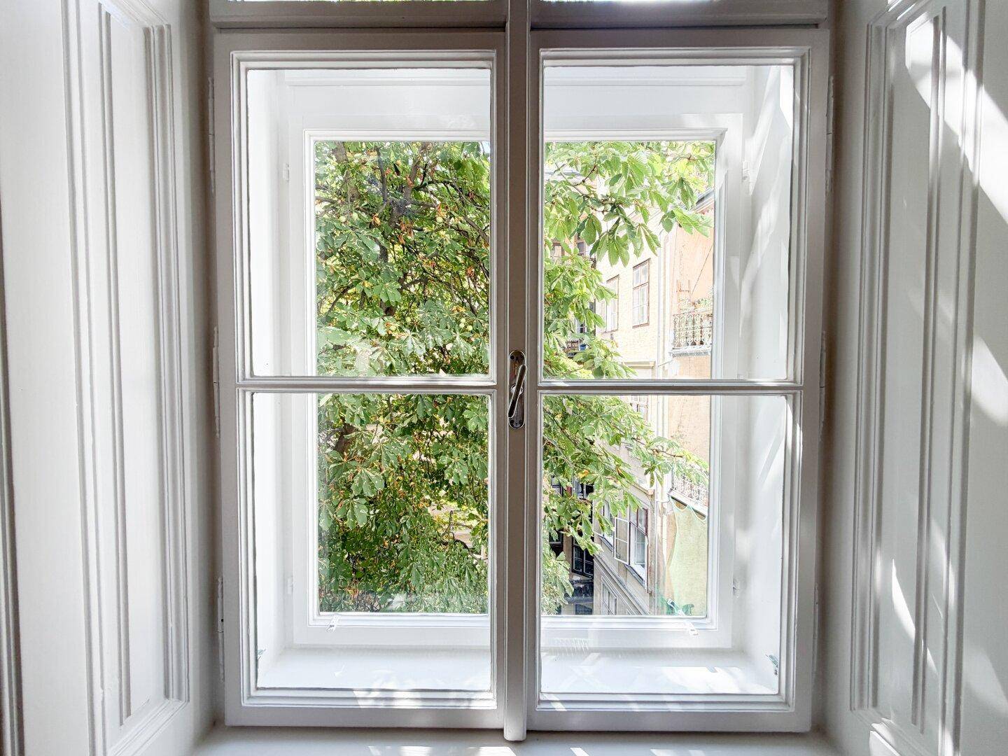 Großes Fenster mit Blick ins Grüne, das viel Tageslicht in den Raum lässt.
