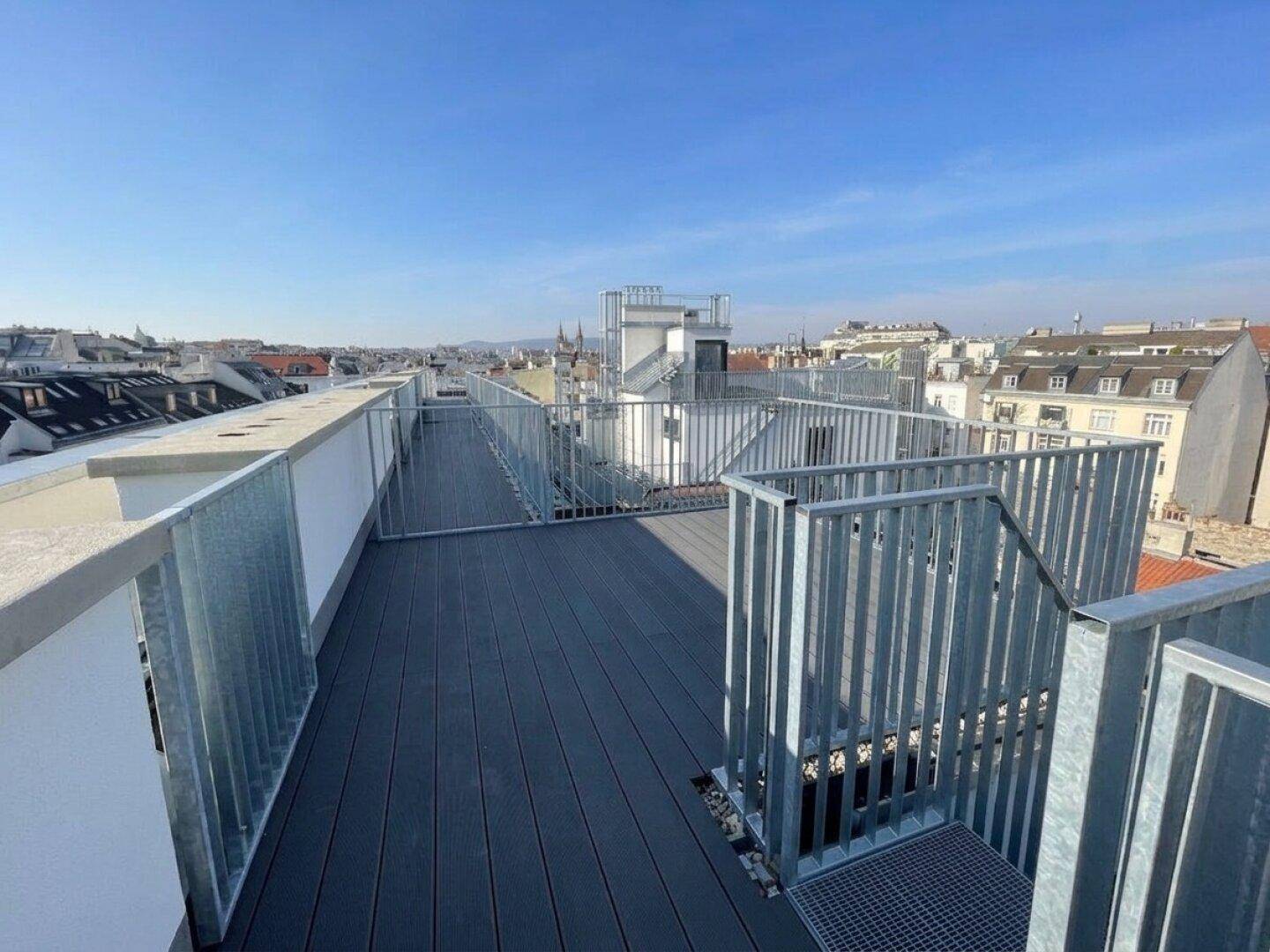 Weitläufige Dachterrasse mit Metallgeländer und Panoramablick über die Stadt.