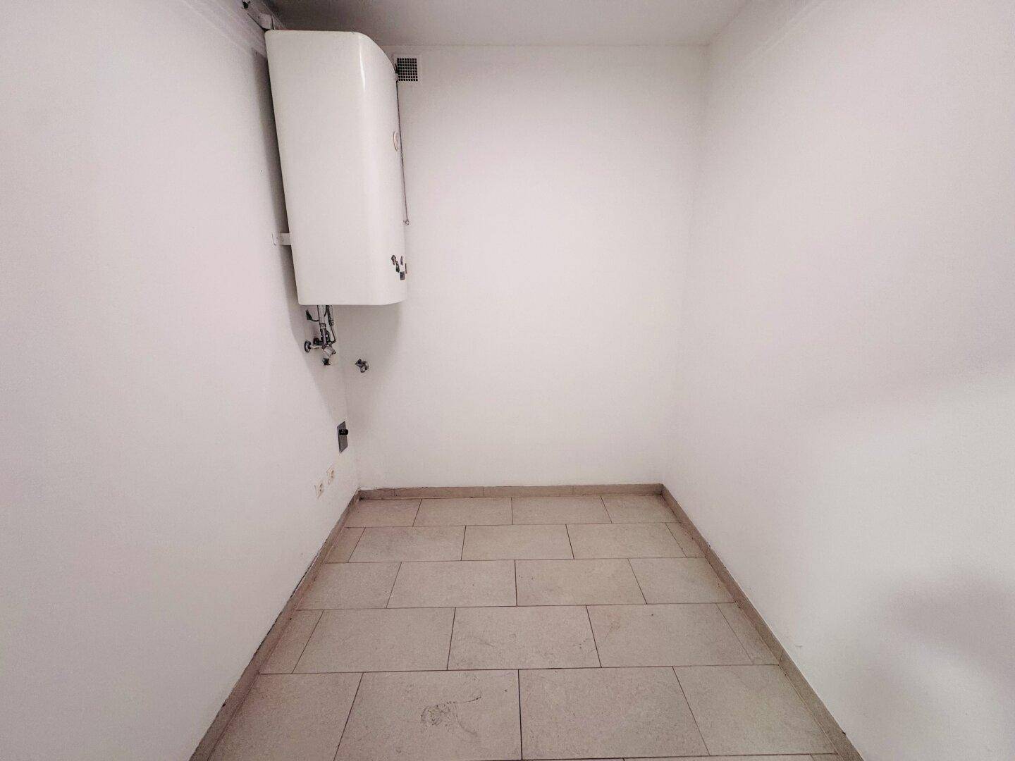 Kleiner Hauswirtschaftsraum mit Fliesenboden und Warmwasserboiler an der Wand.