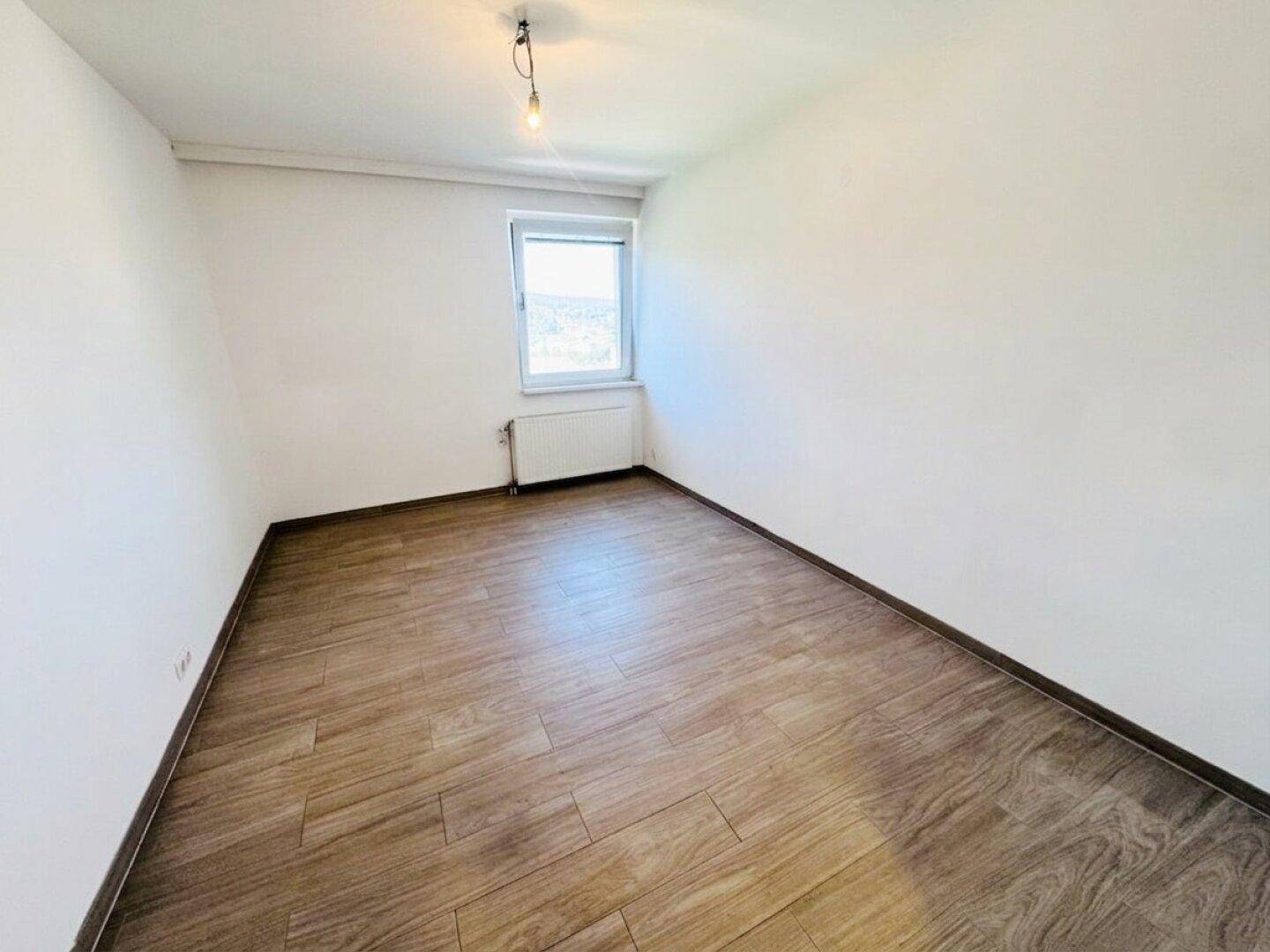 Kleineres, helles Zimmer mit Laminatboden und Fenster, ideal als Schlafzimmer.