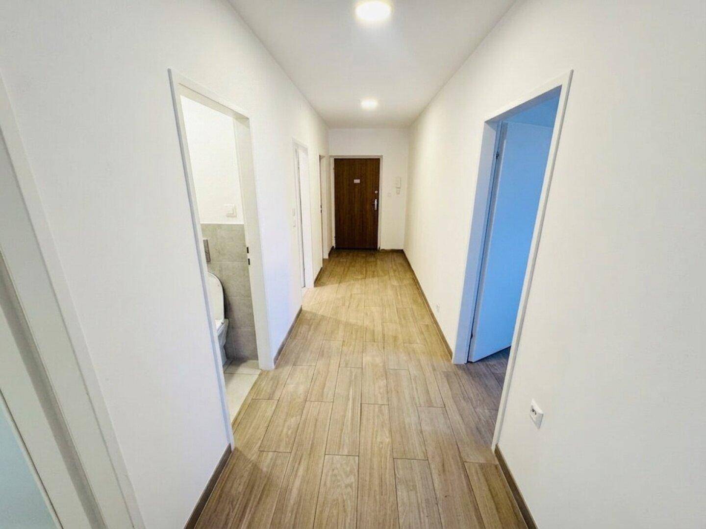 Heller Flur mit Laminatboden und Zugang zu verschiedenen Räumen, inklusive WC.
