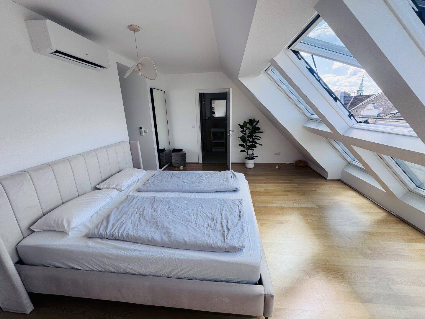 Geräumiges Schlafzimmer im Dachgeschoss mit Klimaanlage und weitem Blick über die Stadt.