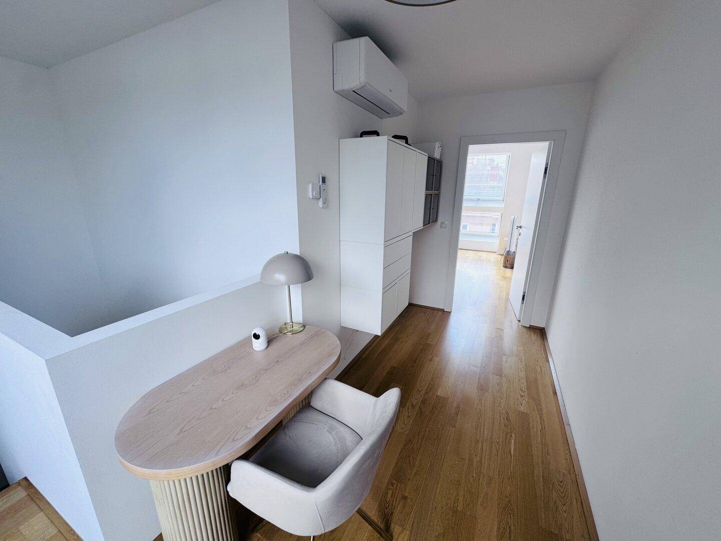 Heller Flurbereich mit kleinem Arbeitsplatz, Einbauschrank und Klimaanlage.
