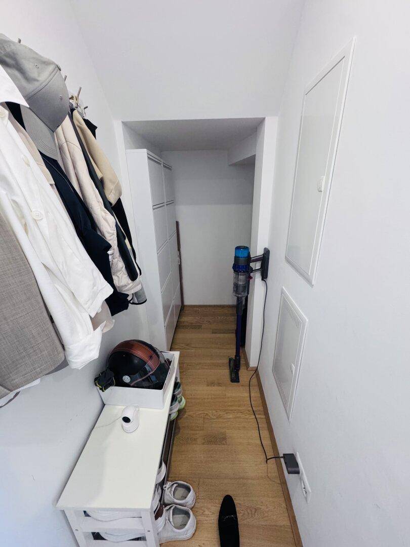 Eingangsbereich mit Garderobe, Schuhregal und Stauraum auf Holzboden.