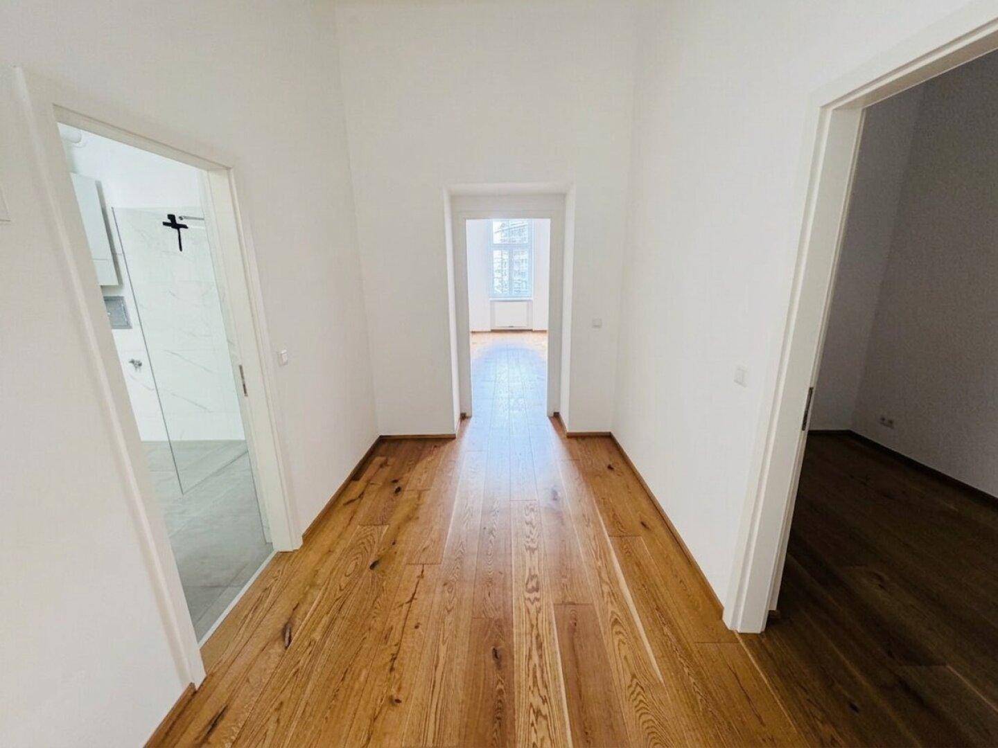 Heller Flur mit Holzboden, der zu verschiedenen Räumen führt und eine offene Atmosphäre schafft.