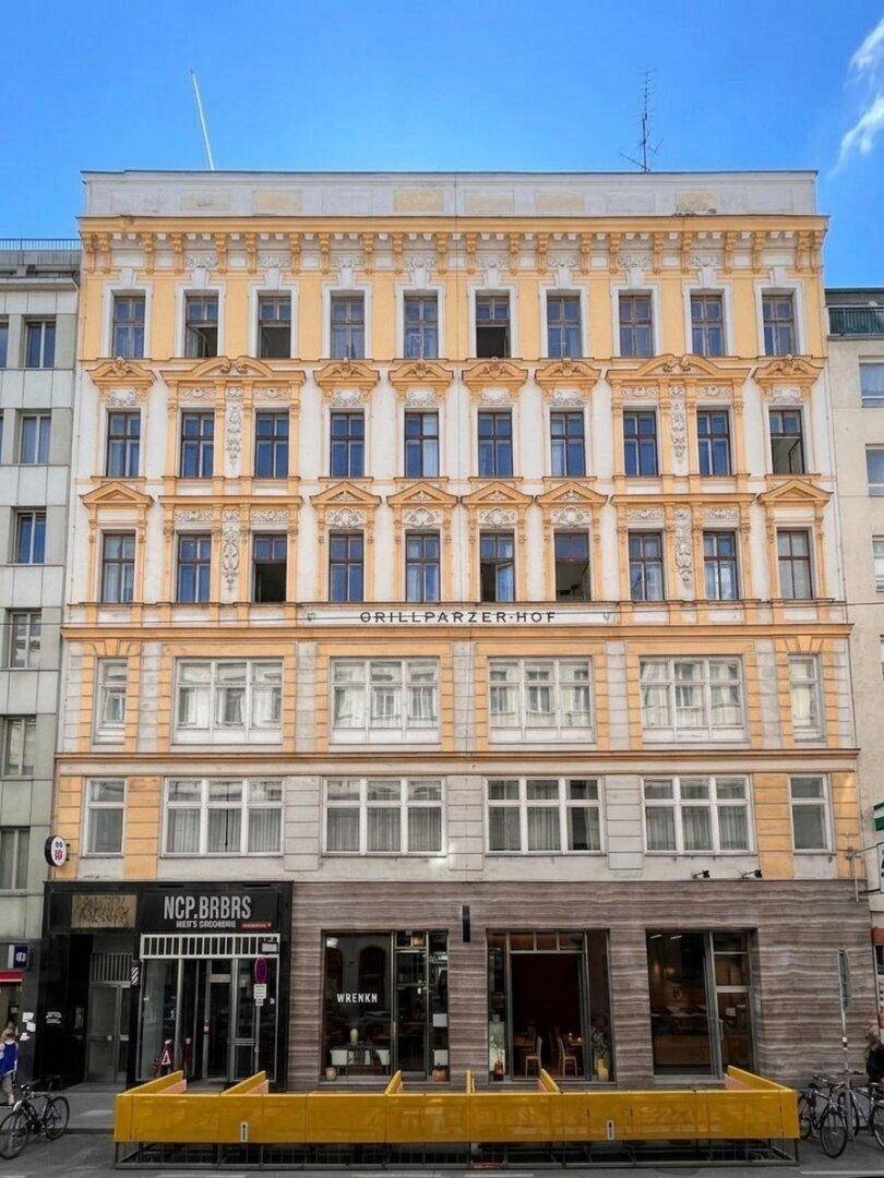 Historisches Gebäude mit gelber Fassade und vielen Fenstern in städtischer Umgebung.