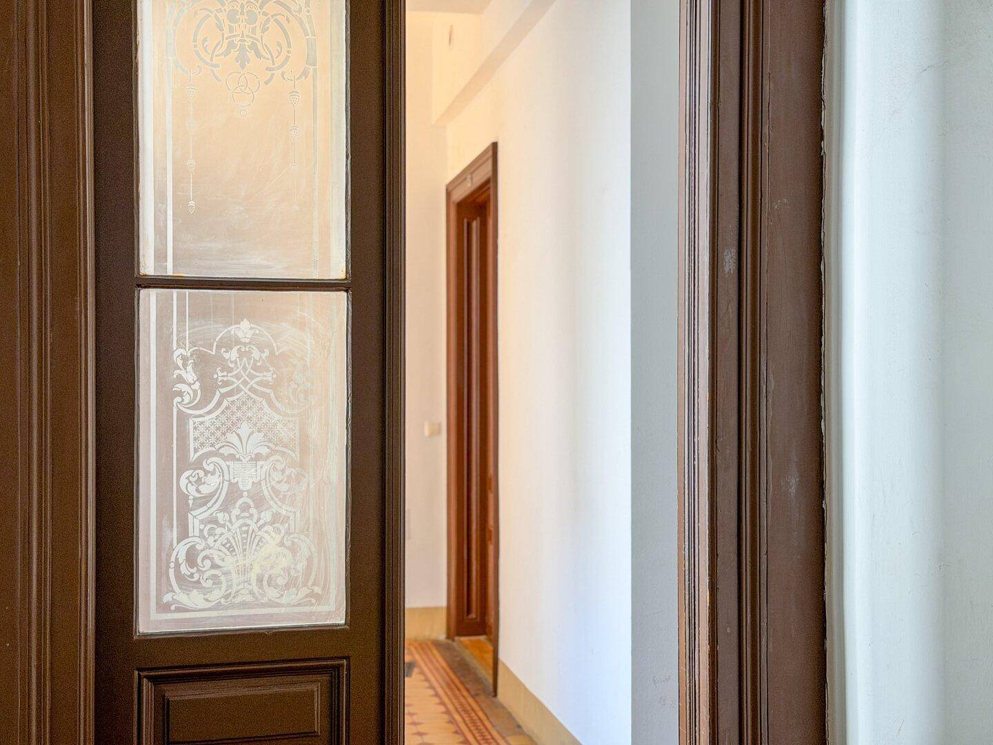 Detailansicht einer kunstvoll verzierten Holztür mit Milchglas im historischen Flur.