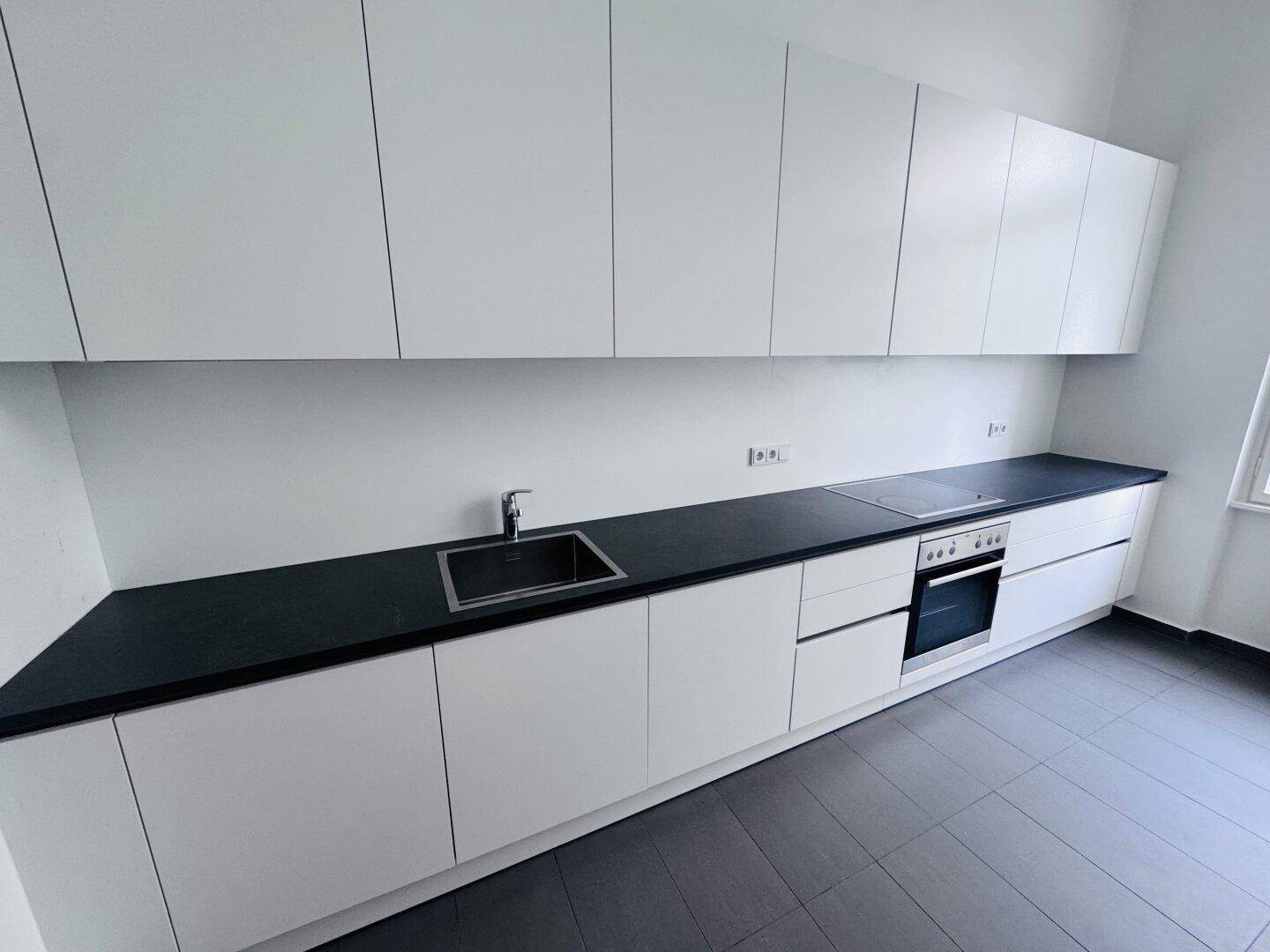 Detailansicht der modernen Einbauküche mit Spüle, Induktionskochfeld und Backofen.
